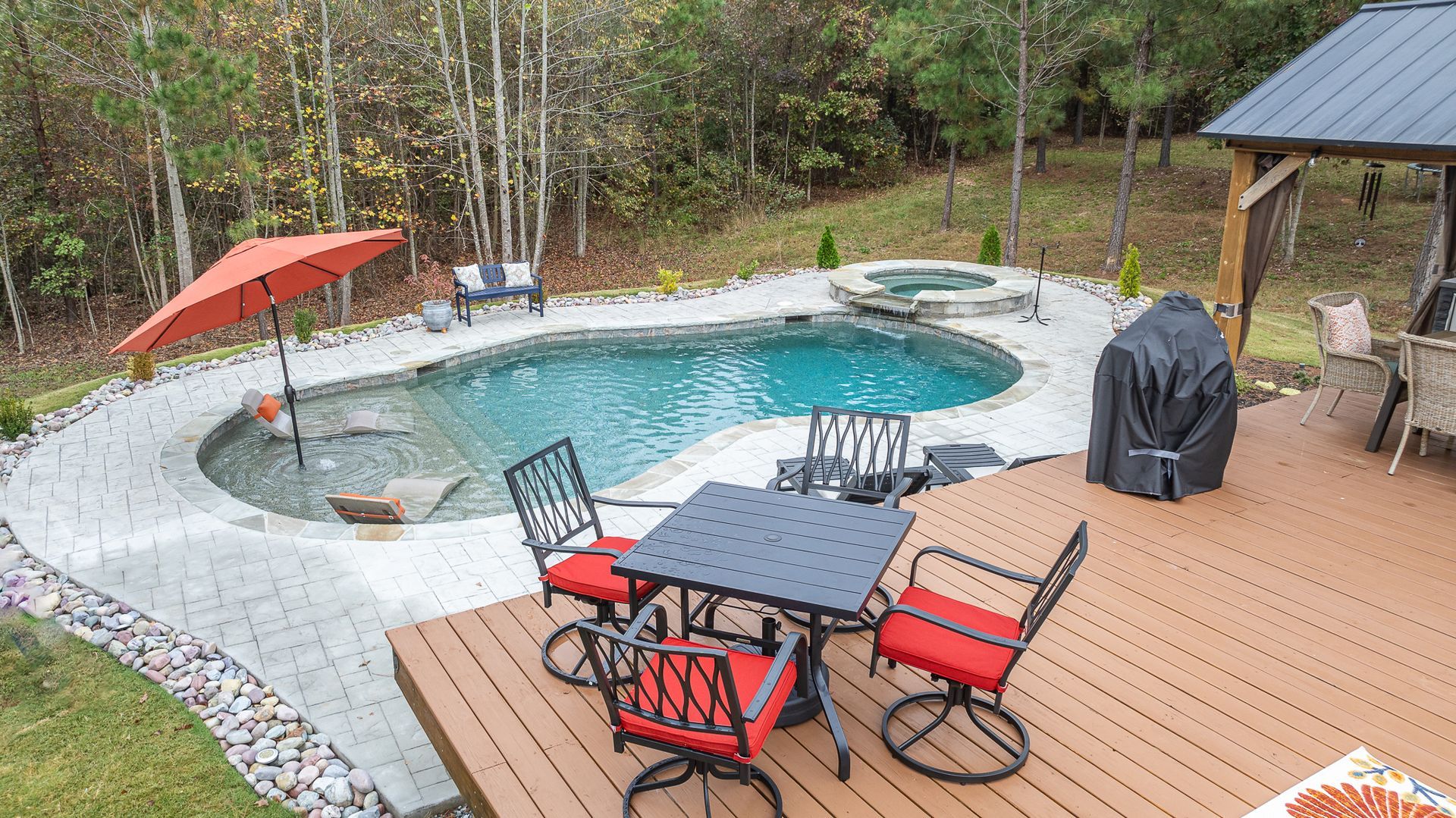 There is a table and chairs on the deck next to a pool.
