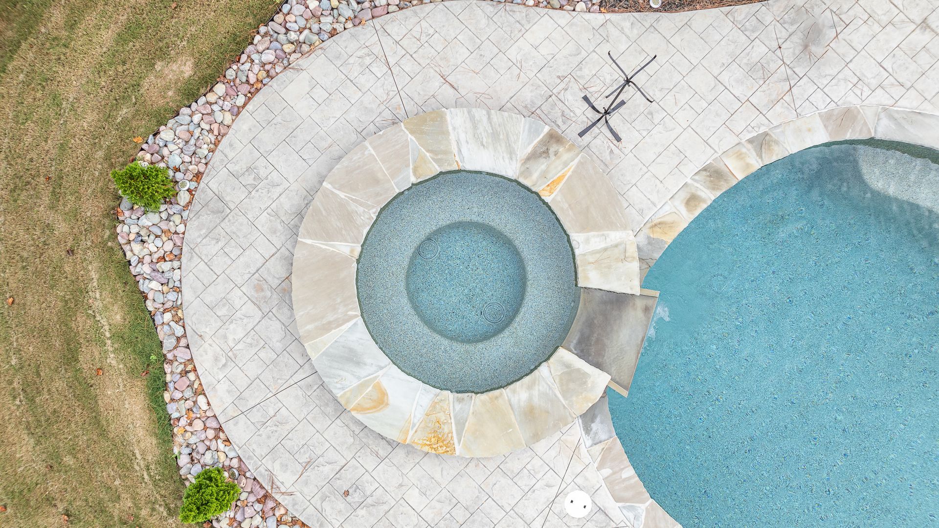 An aerial view of a swimming pool with a hot tub in the middle.