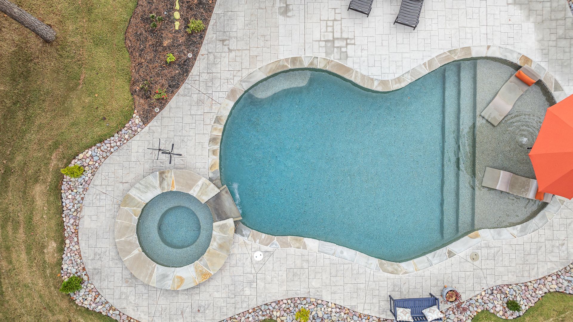 An aerial view of a large swimming pool surrounded by chairs and umbrellas.