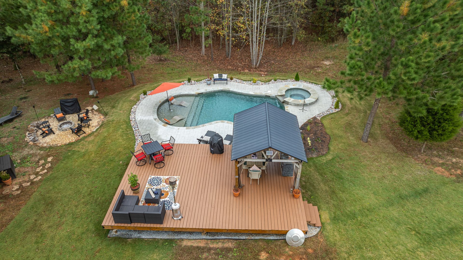 An aerial view of a backyard with a large swimming pool and a wooden deck.