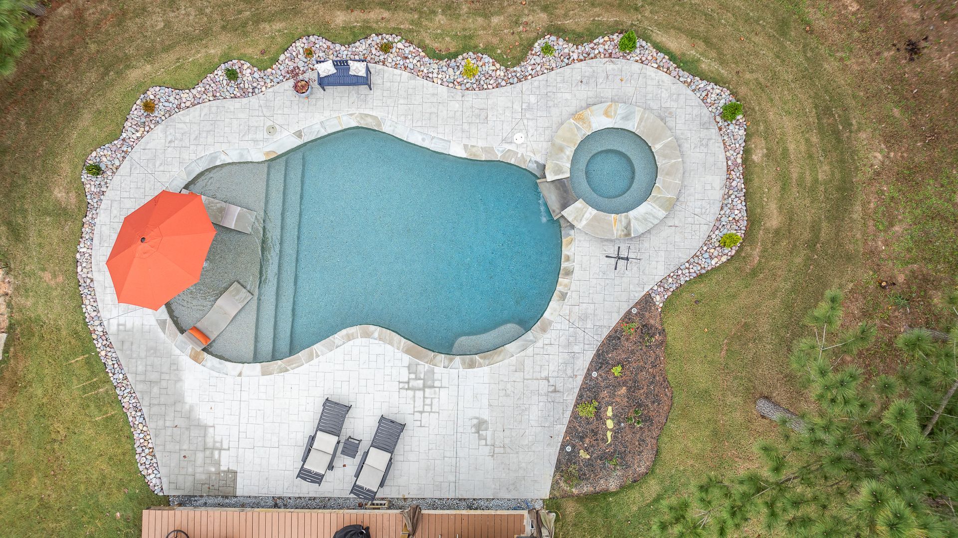 An aerial view of a large swimming pool with an orange umbrella.