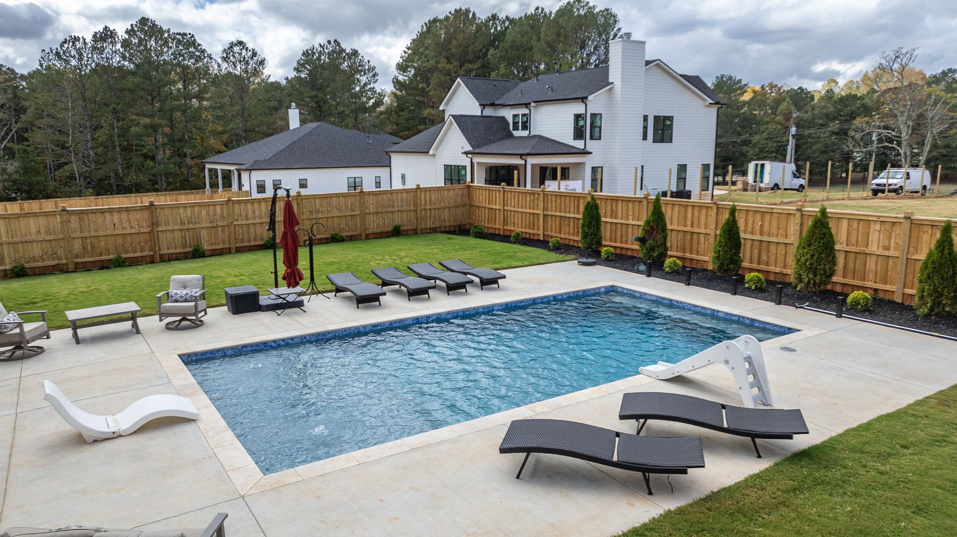 There is a large swimming pool in the backyard of a house.