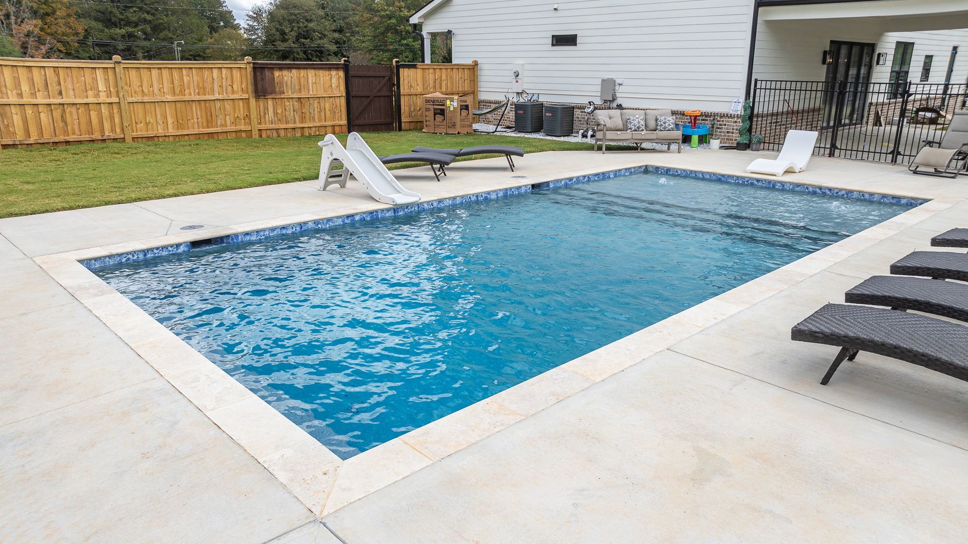 A large swimming pool is in the backyard of a house.