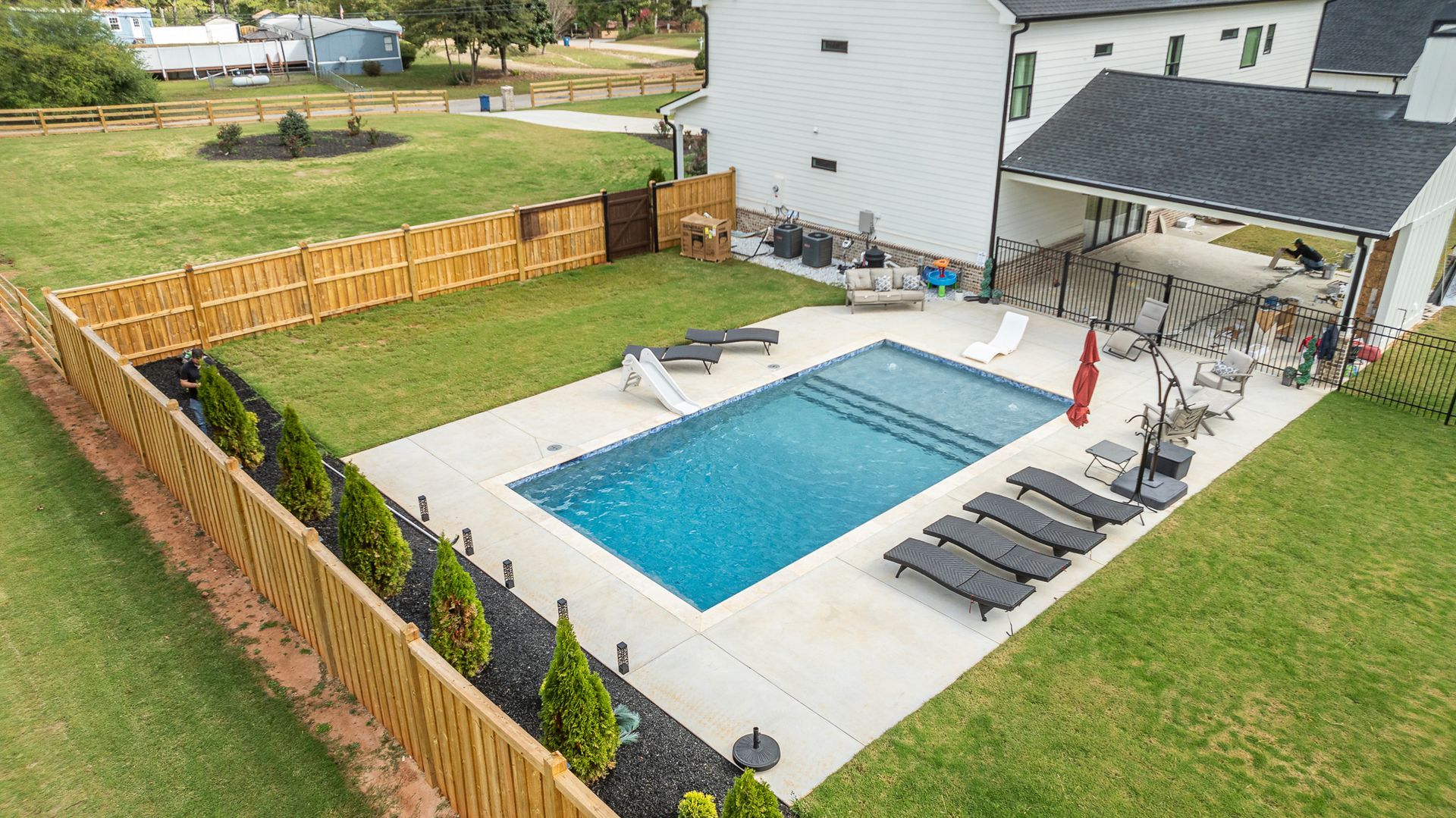 An aerial view of a large swimming pool in the backyard of a house.