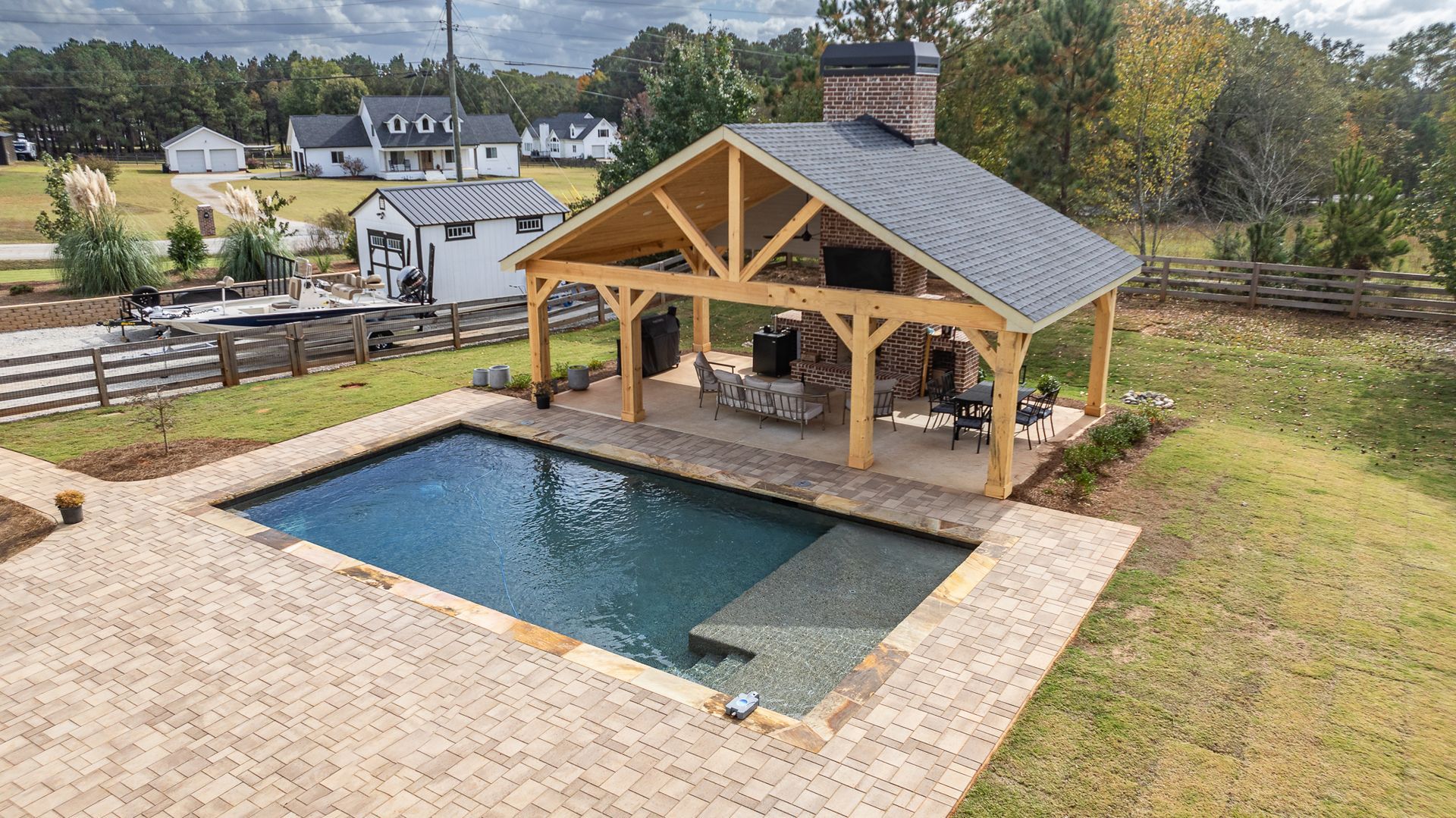 An aerial view of a large swimming pool with a pavilion in the background.