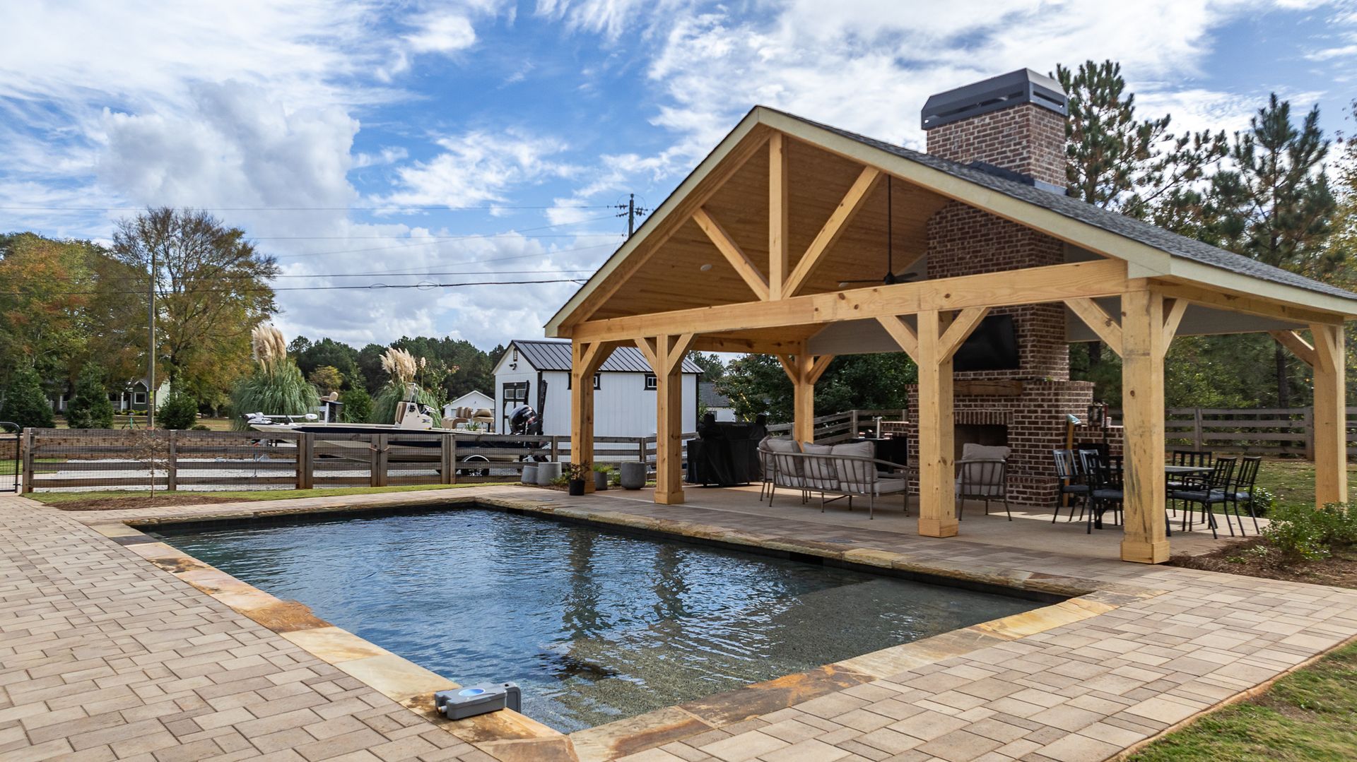 There is a large swimming pool under a wooden pavilion.