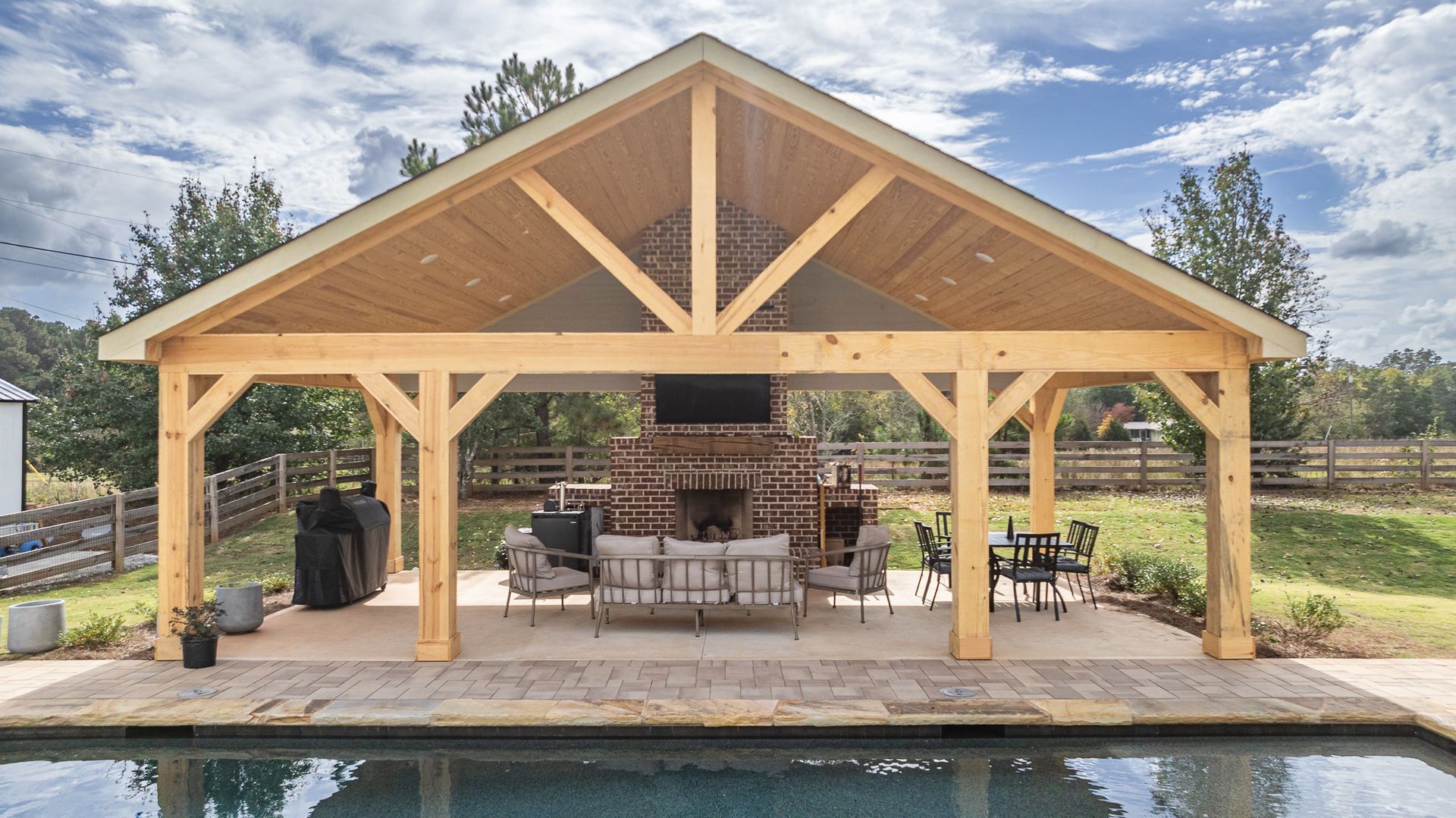 A large wooden pavilion is sitting next to a swimming pool.