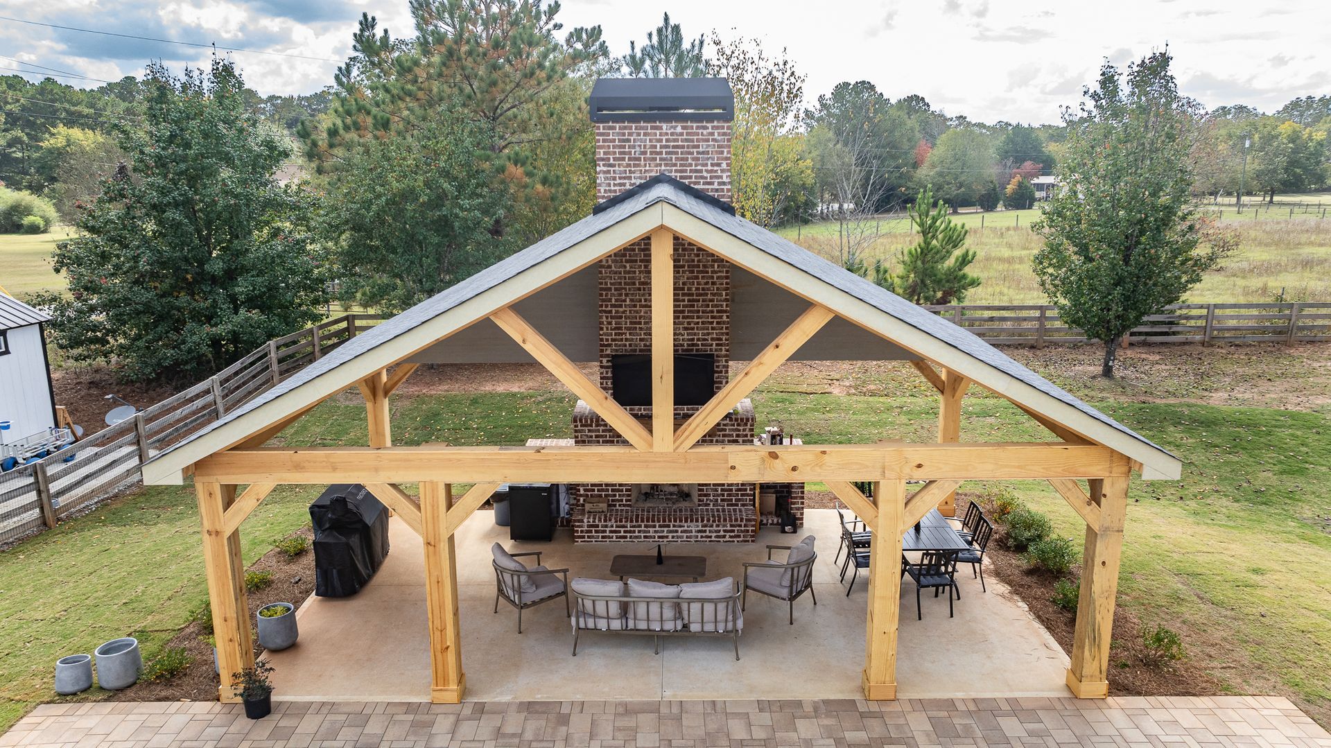 An aerial view of a wooden pavilion with a fireplace and patio furniture.