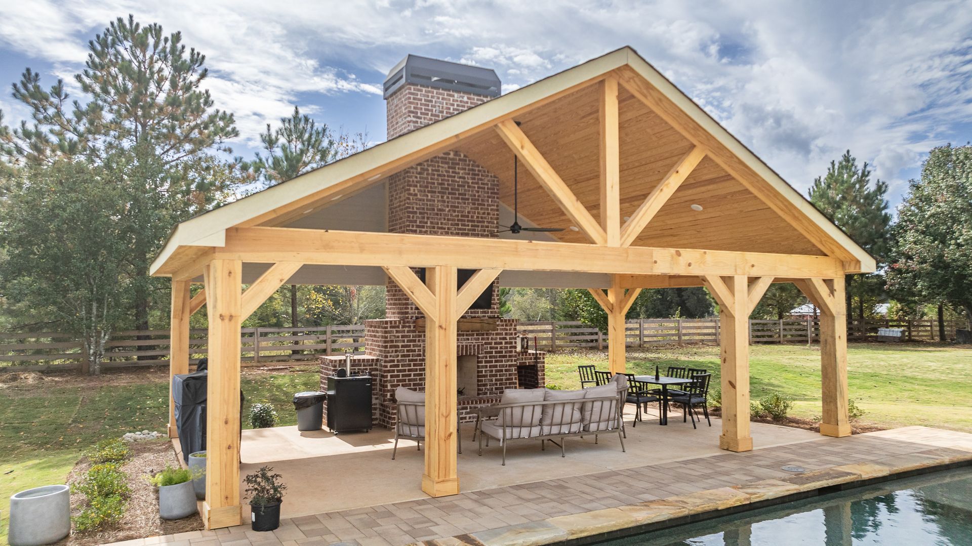 A large wooden pavilion is sitting next to a pool.