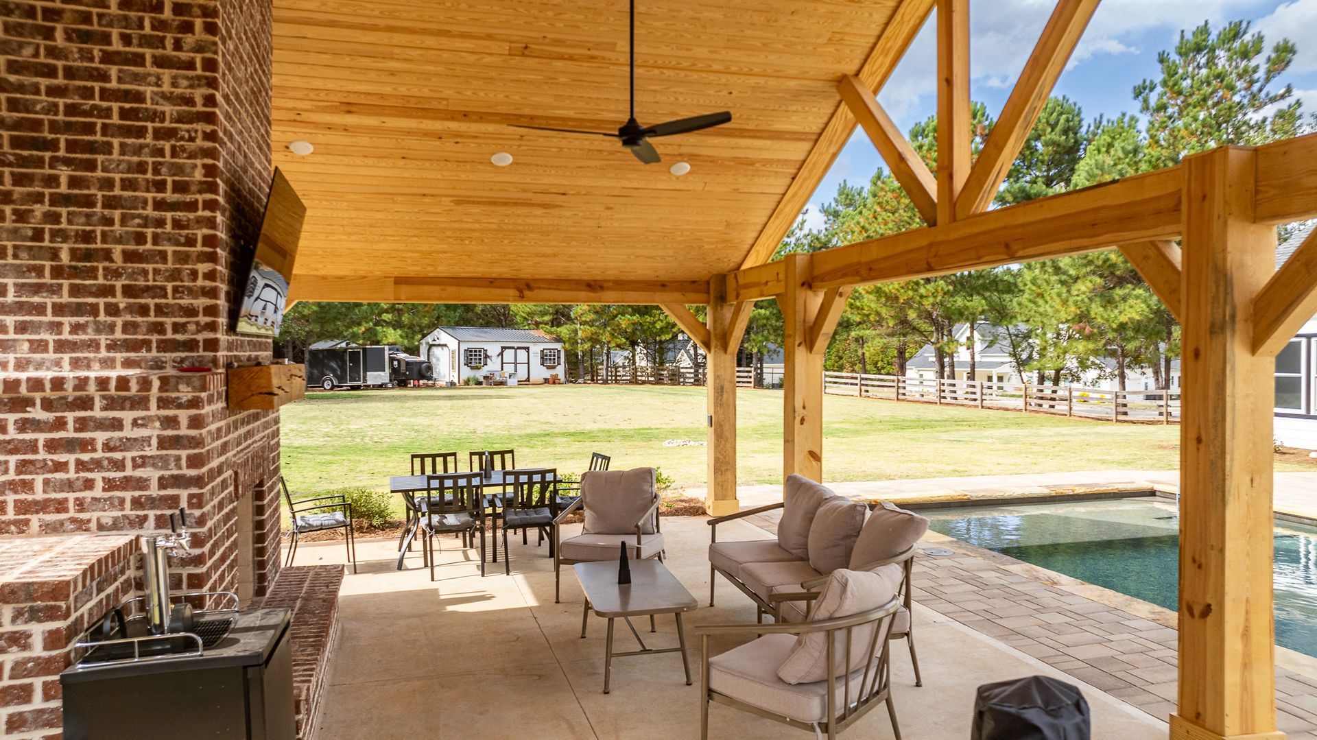 A covered patio with a wooden ceiling and a fireplace.