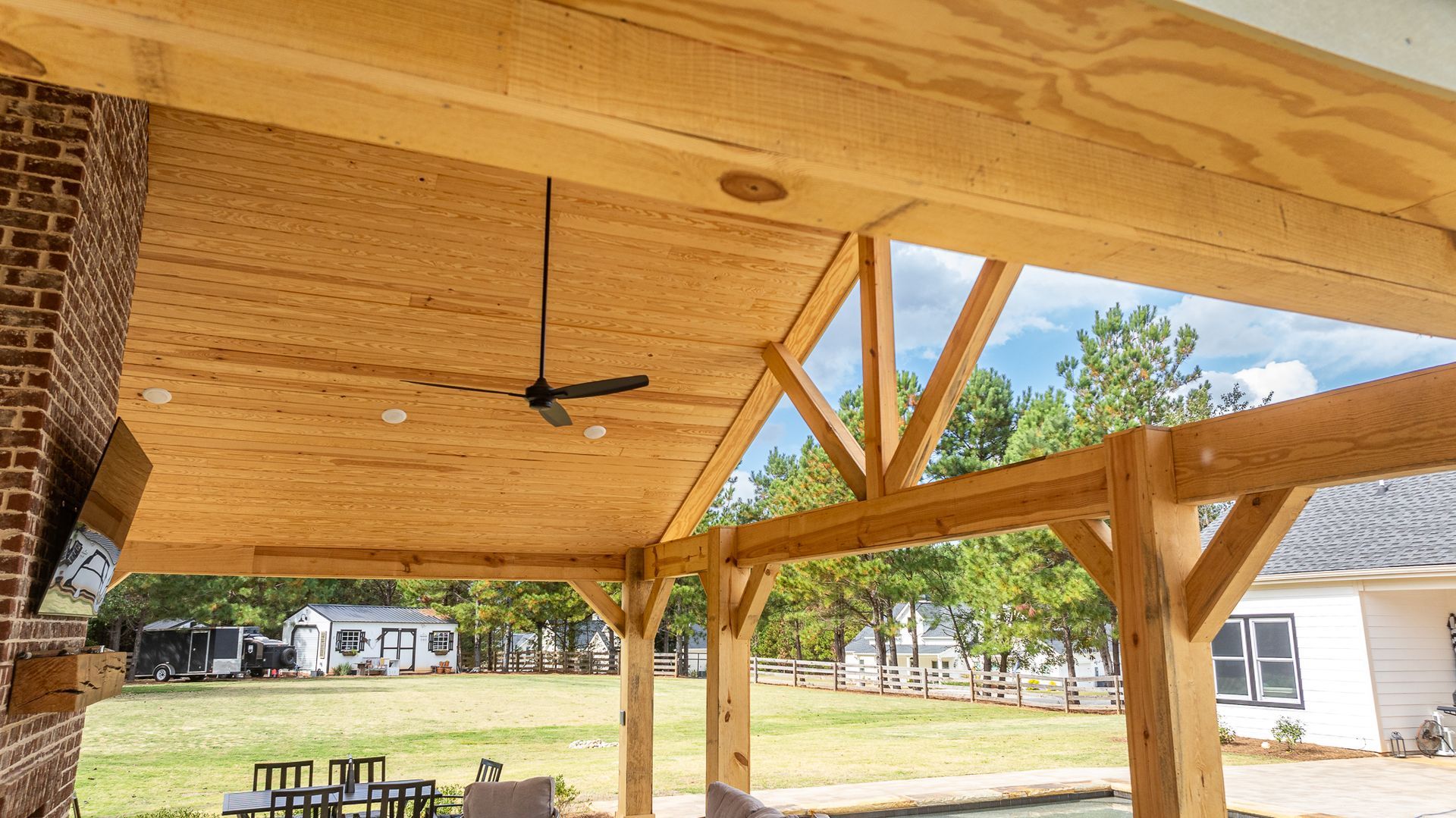 There is a ceiling fan hanging from the ceiling of a wooden structure.