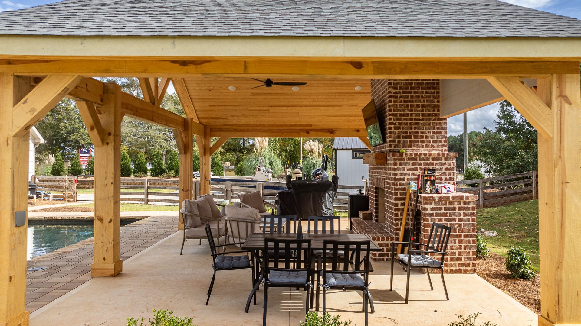 A wooden gazebo with a table and chairs underneath it.