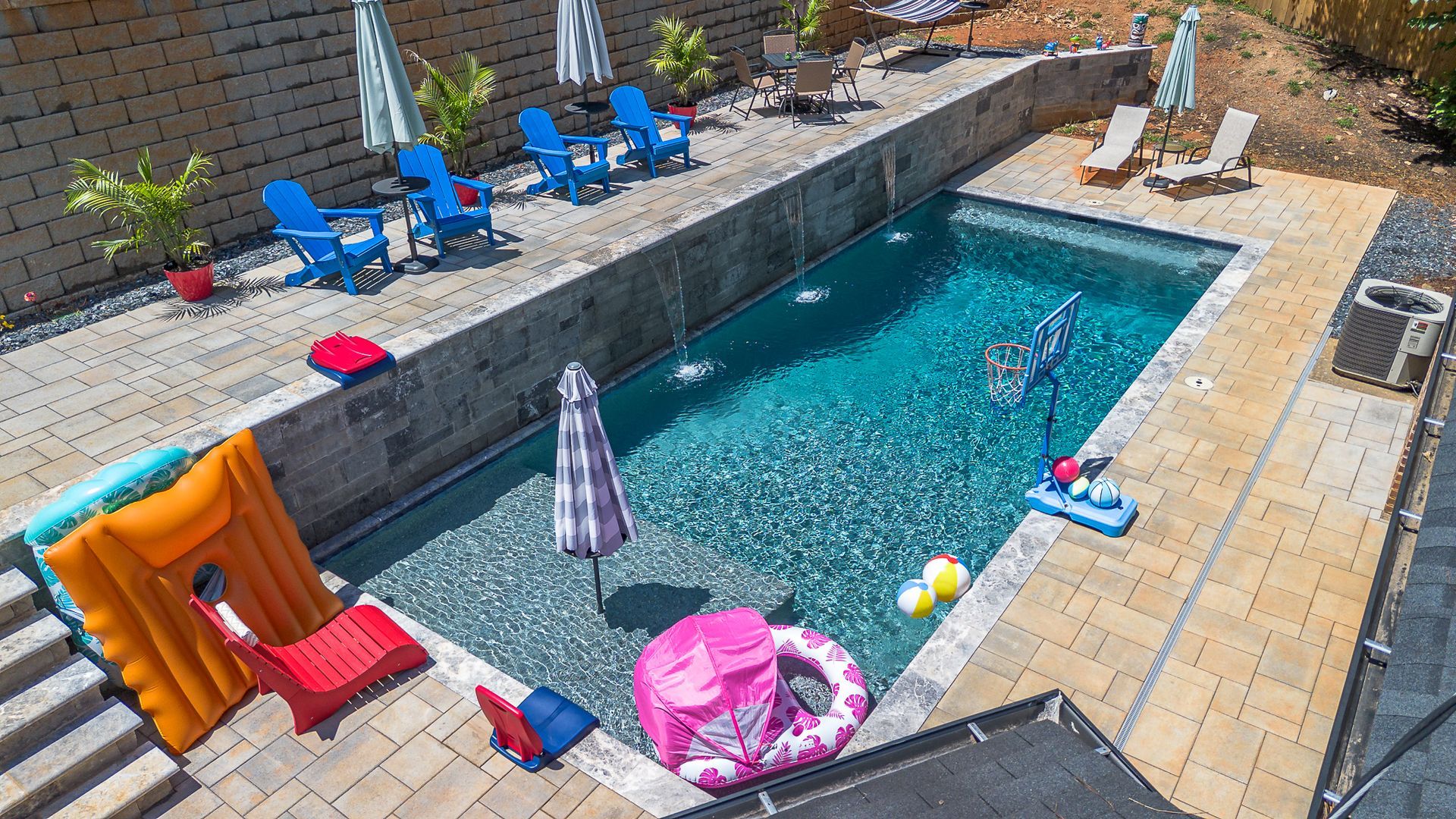 An aerial view of a large swimming pool surrounded by chairs and umbrellas.