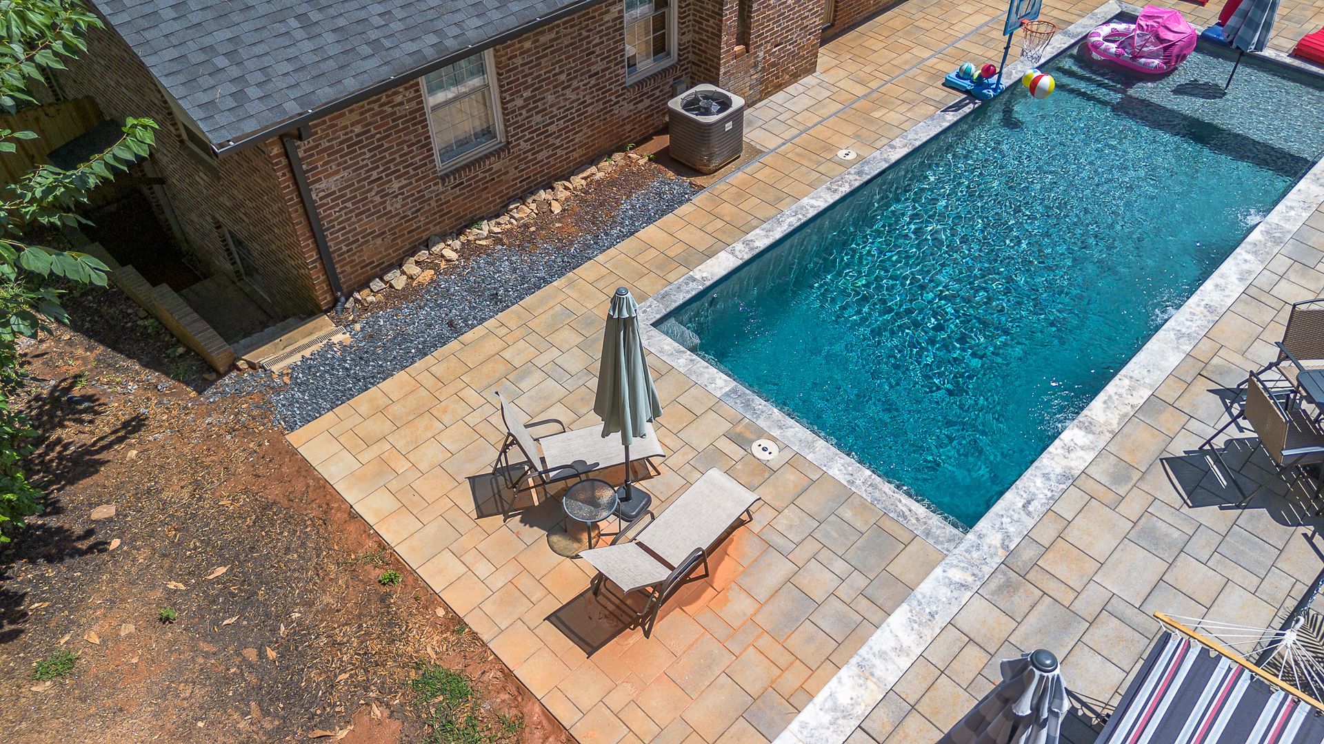 Backyard pool with patio, lounge chairs, and a small building.
