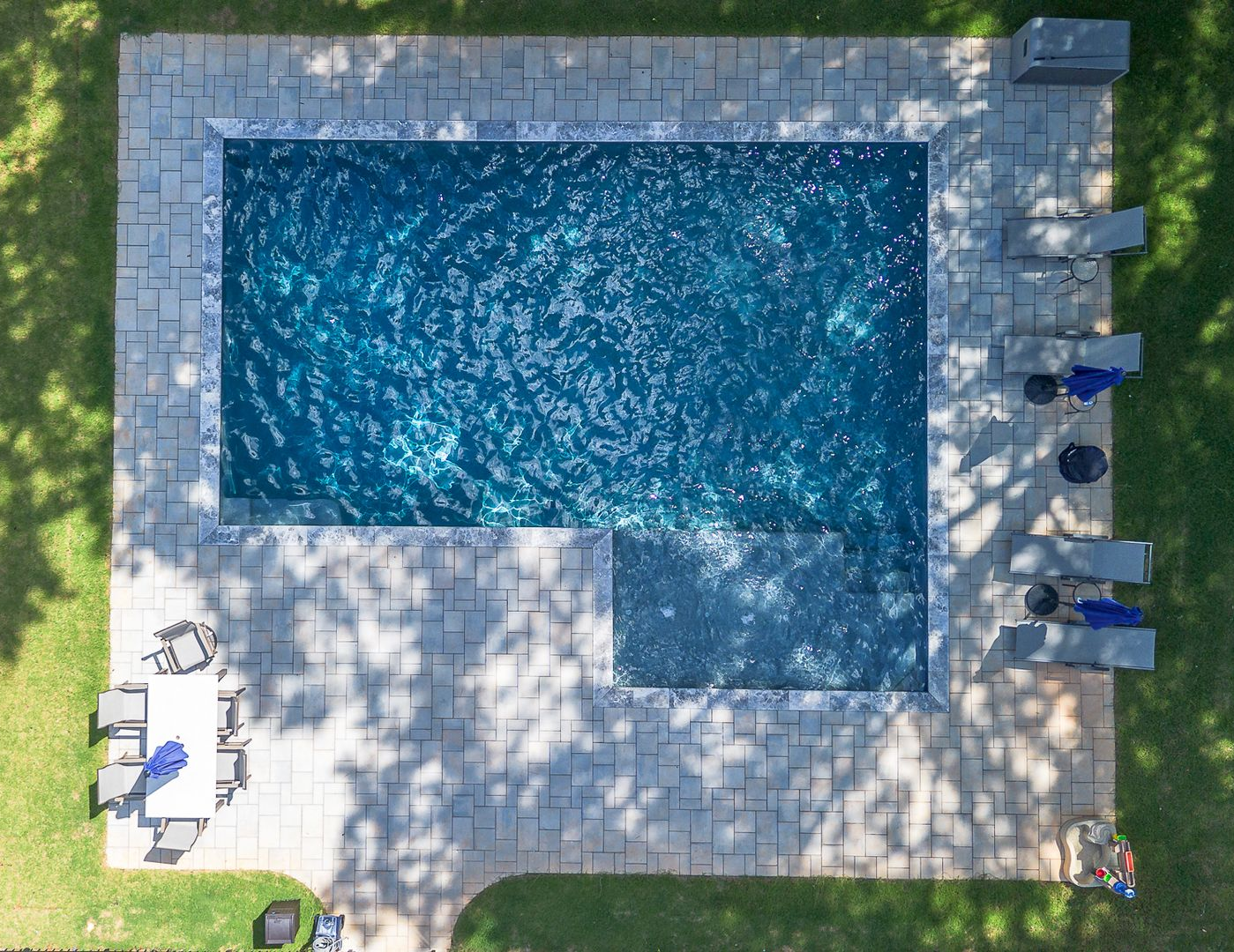 A large swimming pool is surrounded by a wooden fence and chairs.