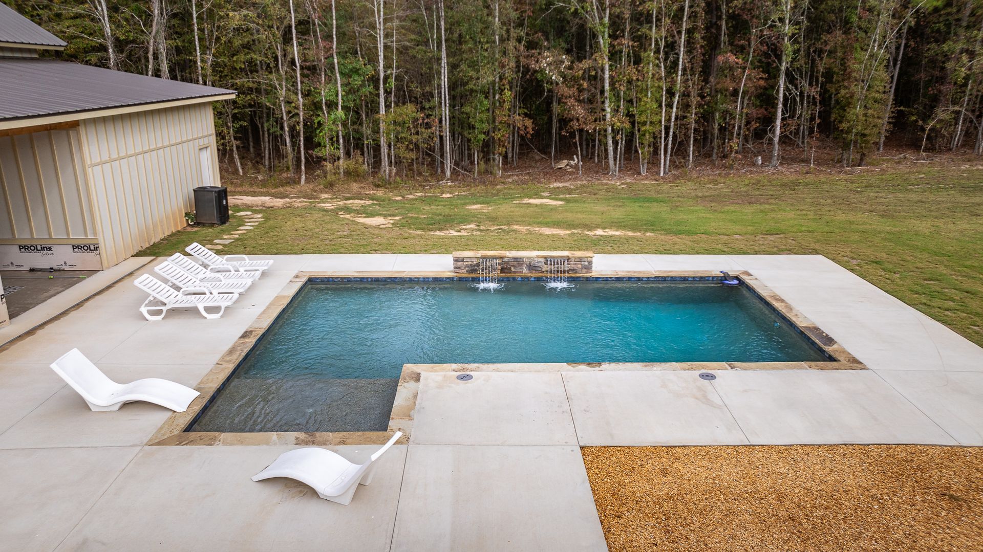 There is a large swimming pool in the backyard of a house.