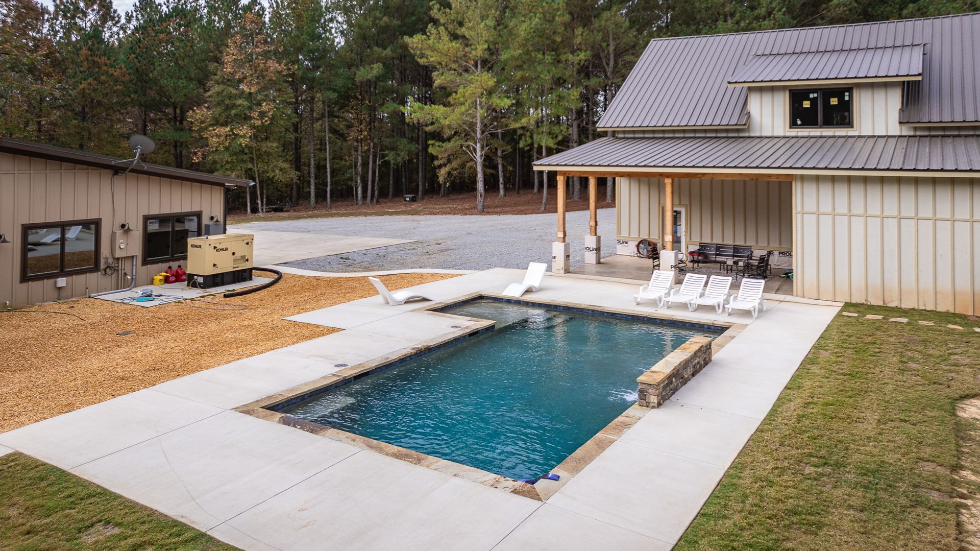 A large swimming pool is in the backyard of a house.