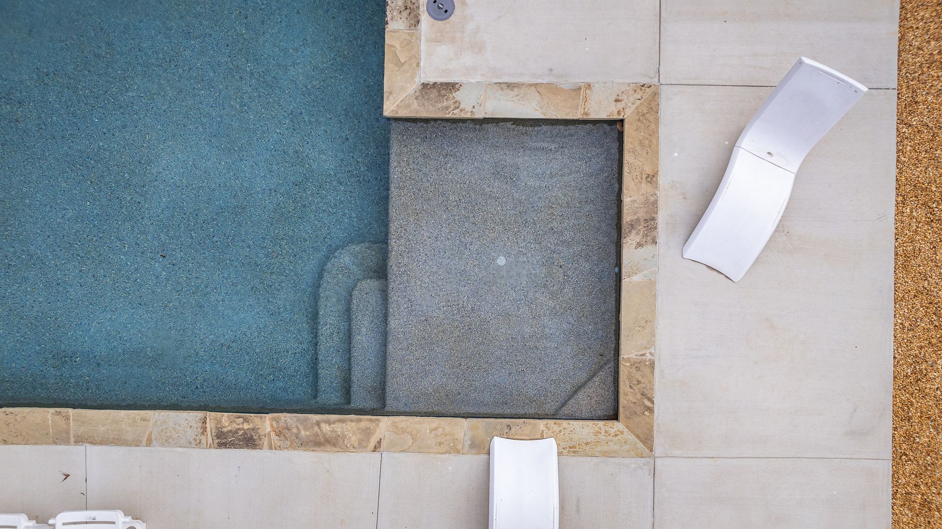 An aerial view of a swimming pool with two chairs next to it.
