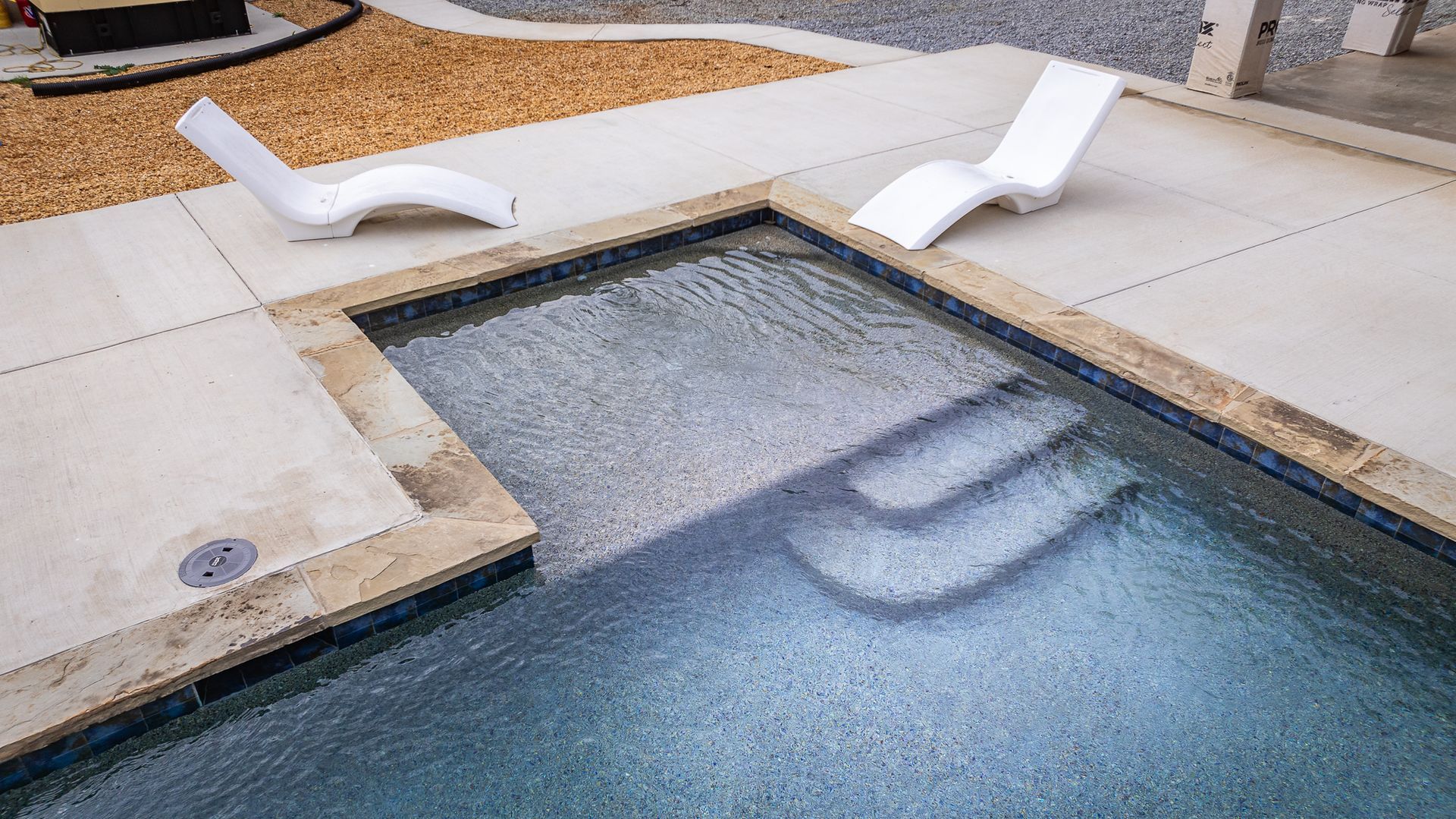 Two white lounge chairs are sitting next to a swimming pool.
