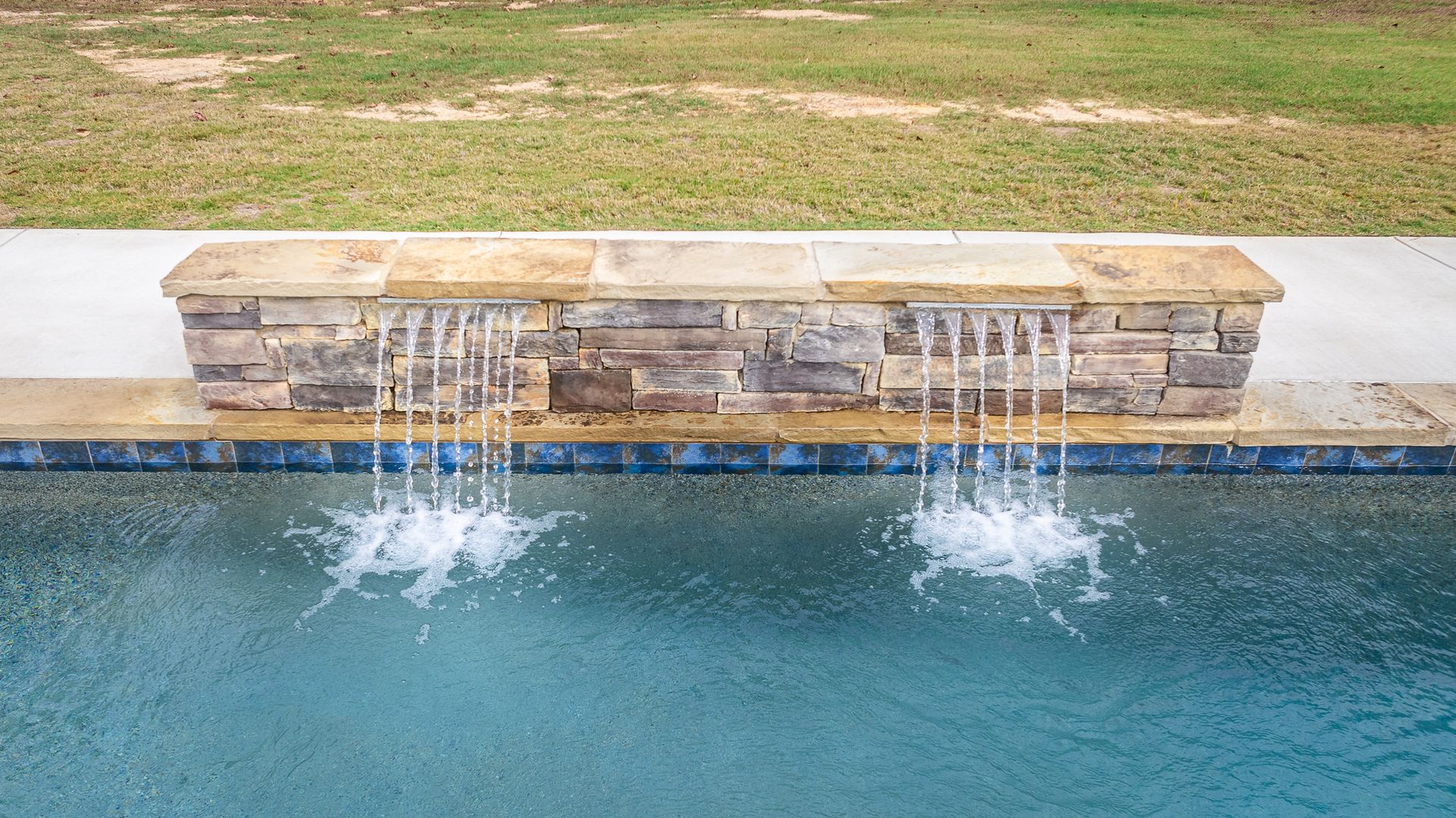 There is a waterfall in the middle of a swimming pool.