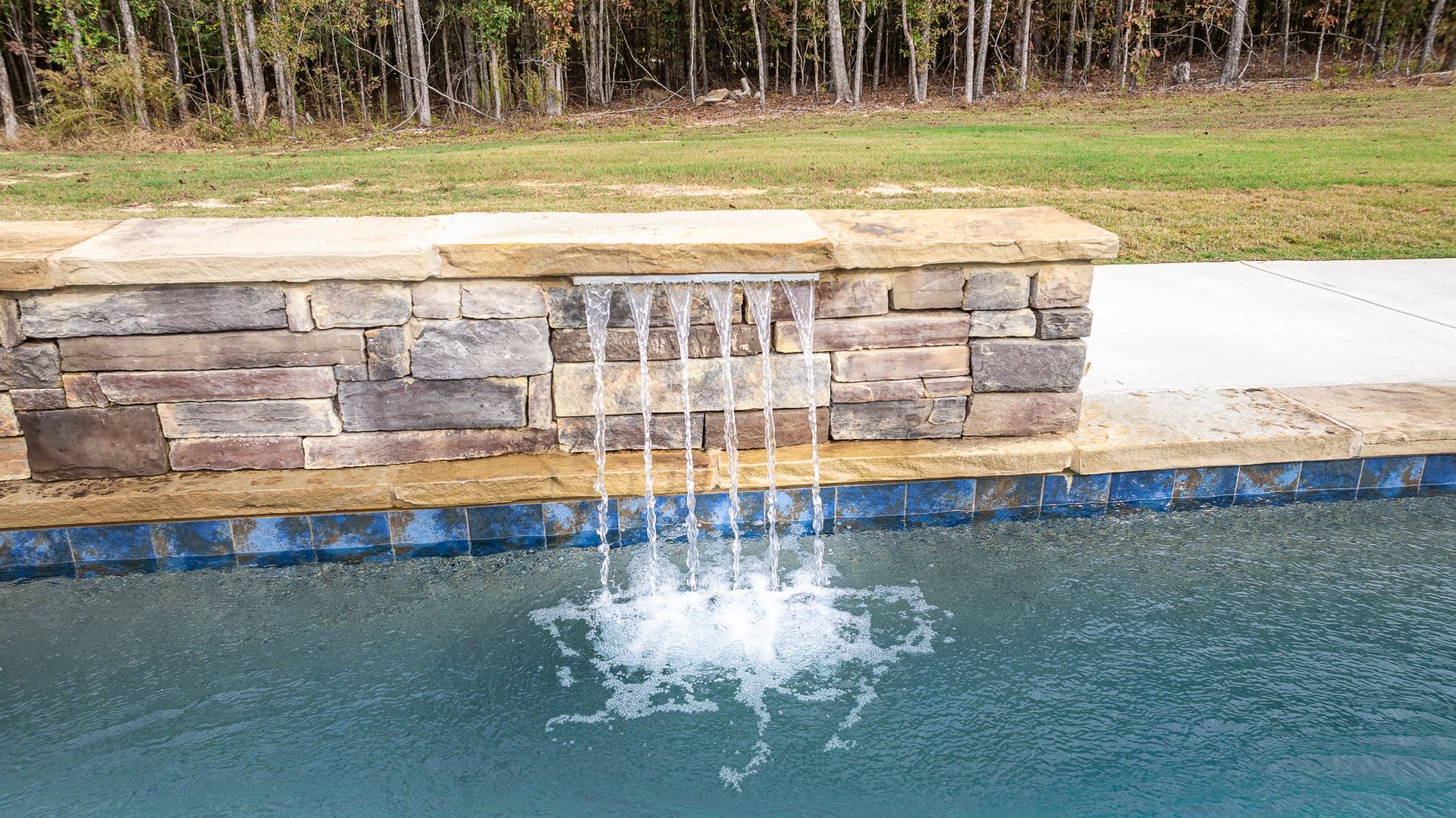 There is a waterfall in the middle of a swimming pool.