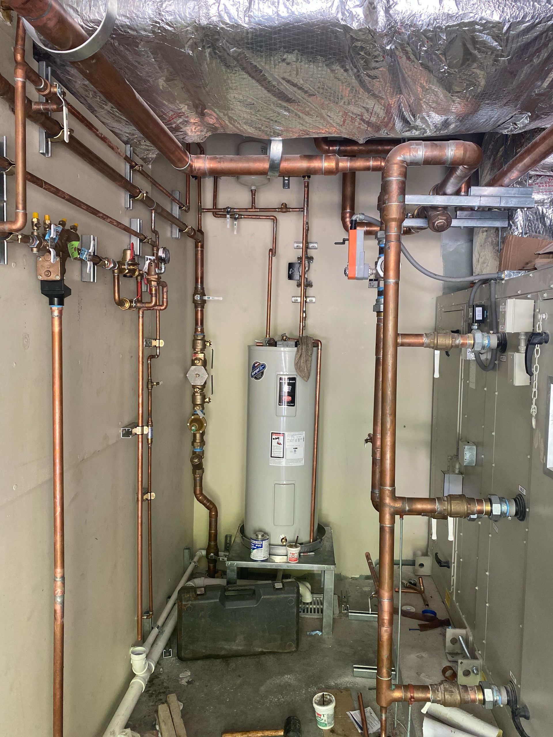A room filled with copper pipes and a water heater