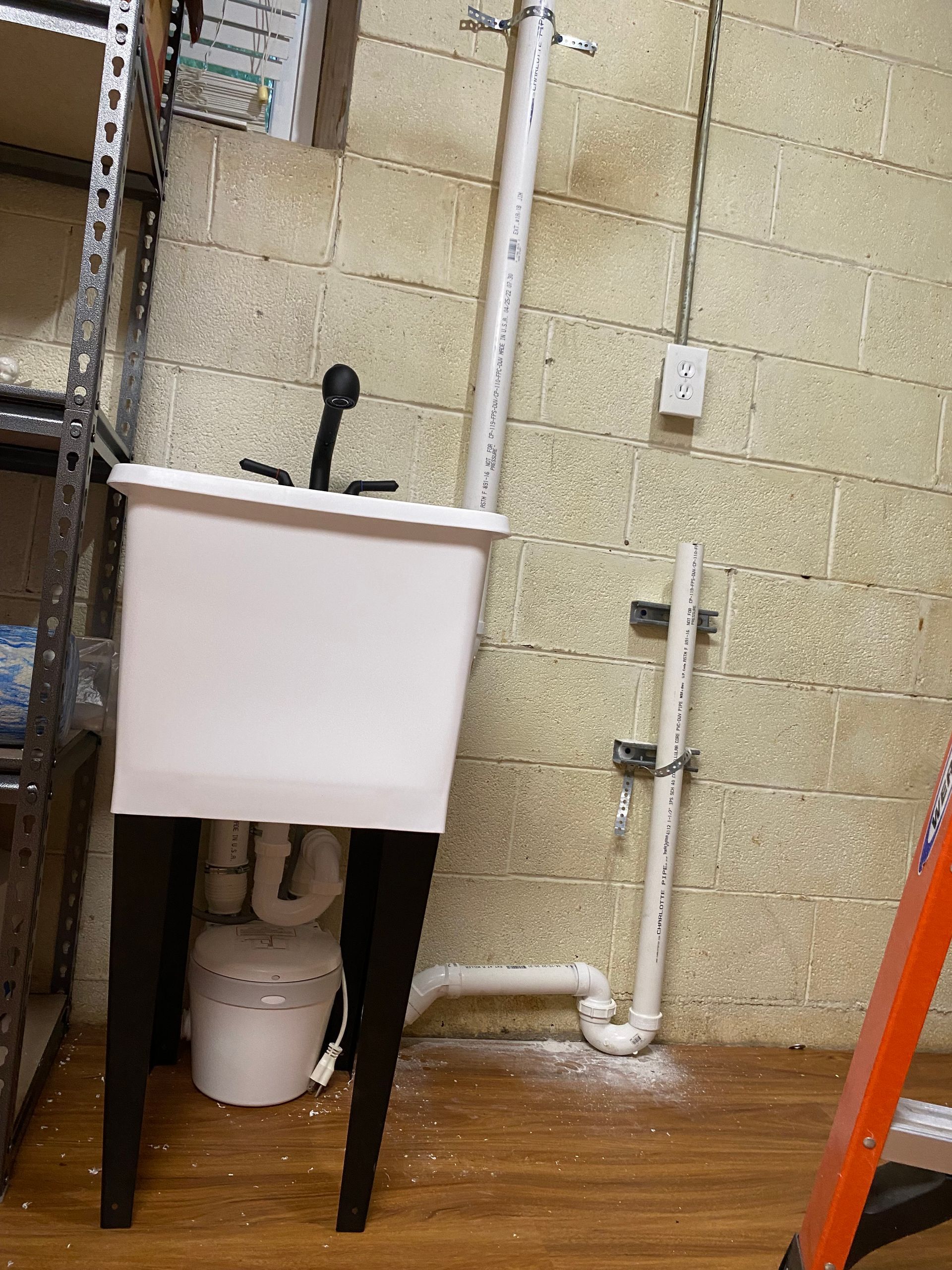 A white sink is sitting in a room next to a ladder.