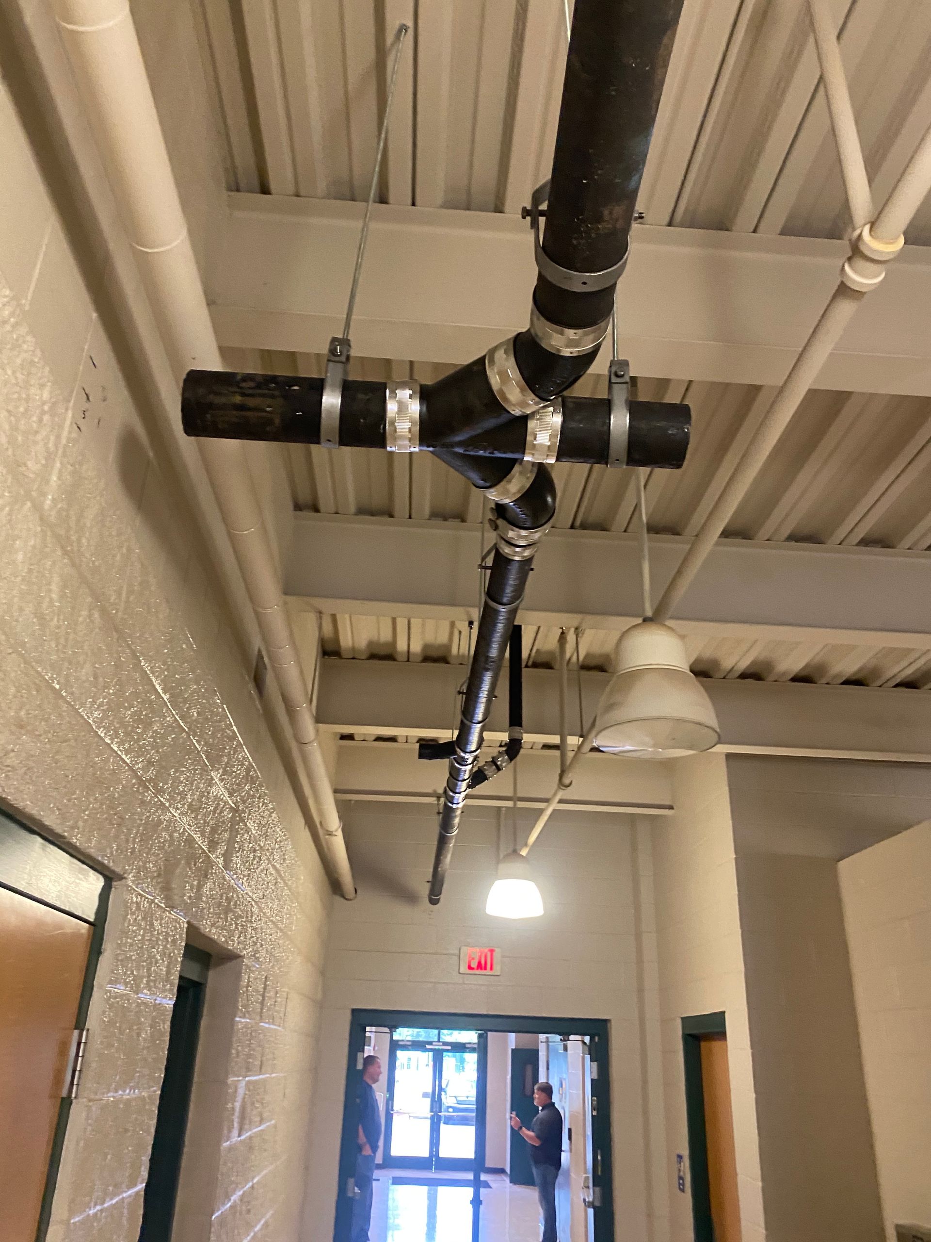 A pipe is hanging from the ceiling in a hallway.