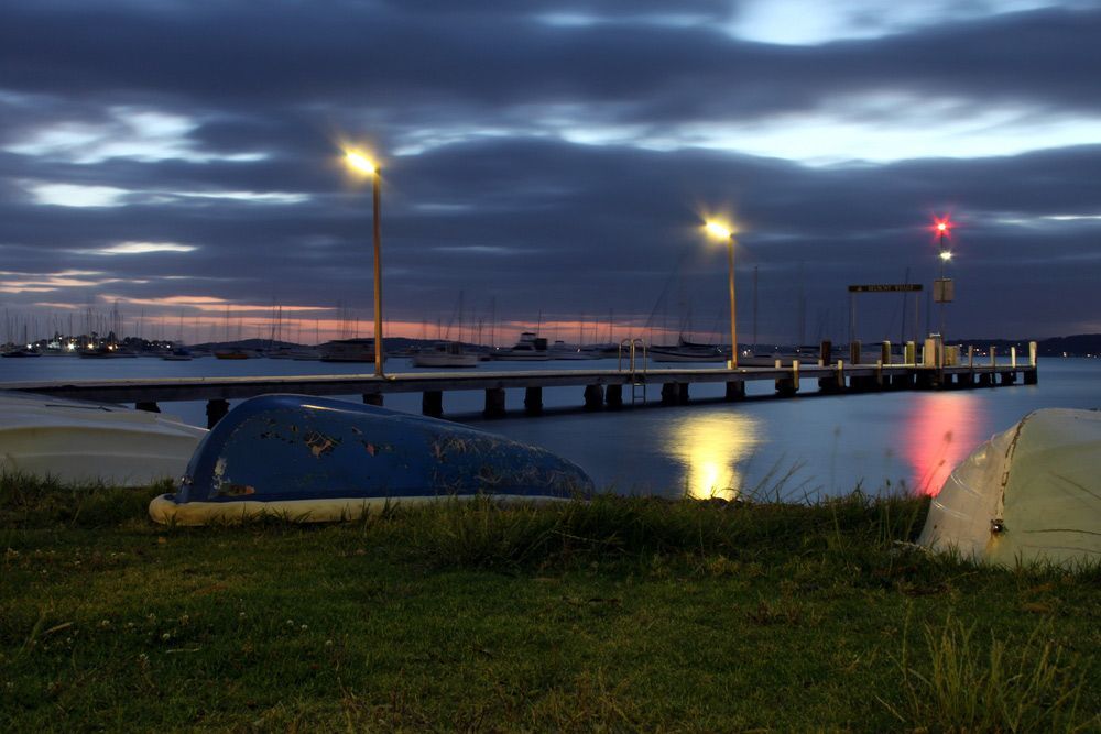 A Boat Is Sitting on The Grass Near a Dock at Night — J’s Concreting & Carpentry in Port Macquarie, NSW