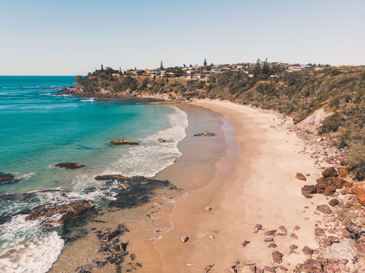 An Aerial View of A Sandy Beach Next to The Ocean — J’s Concreting & Carpentry in Bonny Hills, NSW