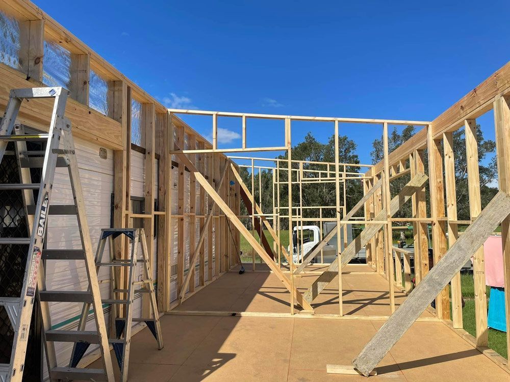 A Wooden House Is Being Built with A Ladder and Stairs — J’s Concreting & Carpentry in Kendall, NSW