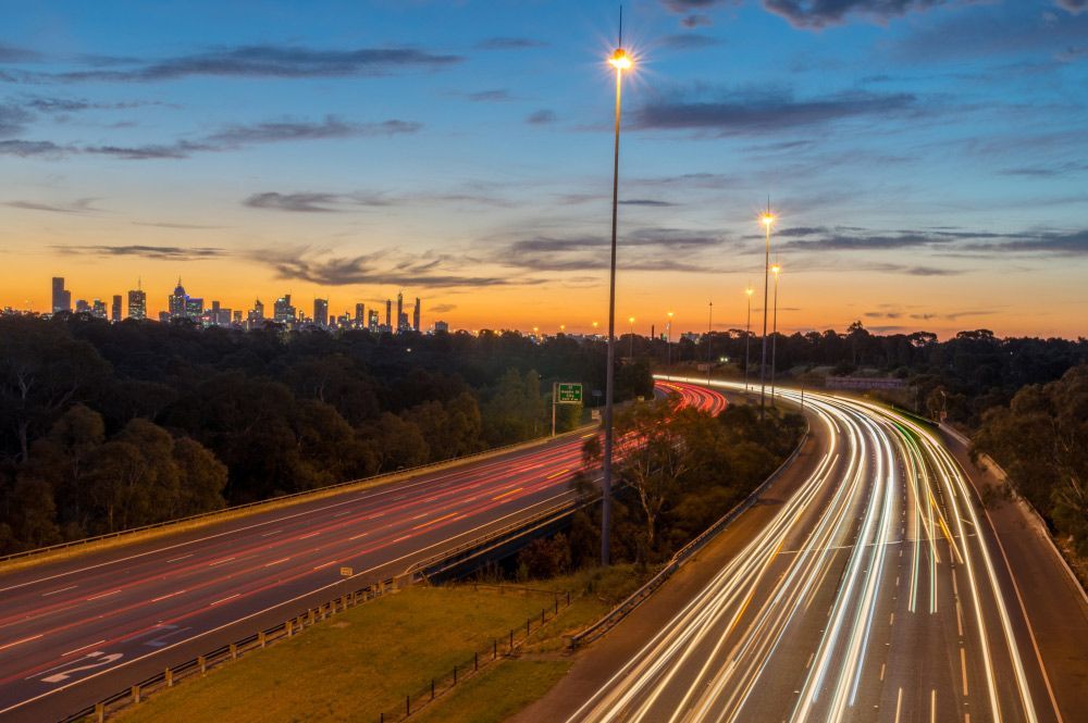 A Highway with A City Skyline in The Background at Sunset — J’s Concreting & Carpentry in Kew, NSW
