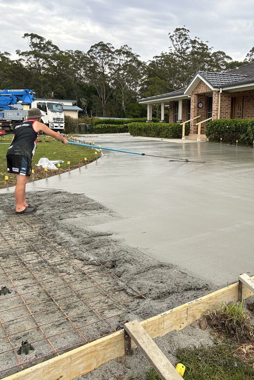 A Man Is Working on A Concrete Driveway — J’s Concreting & Carpentry in Kew, NSW