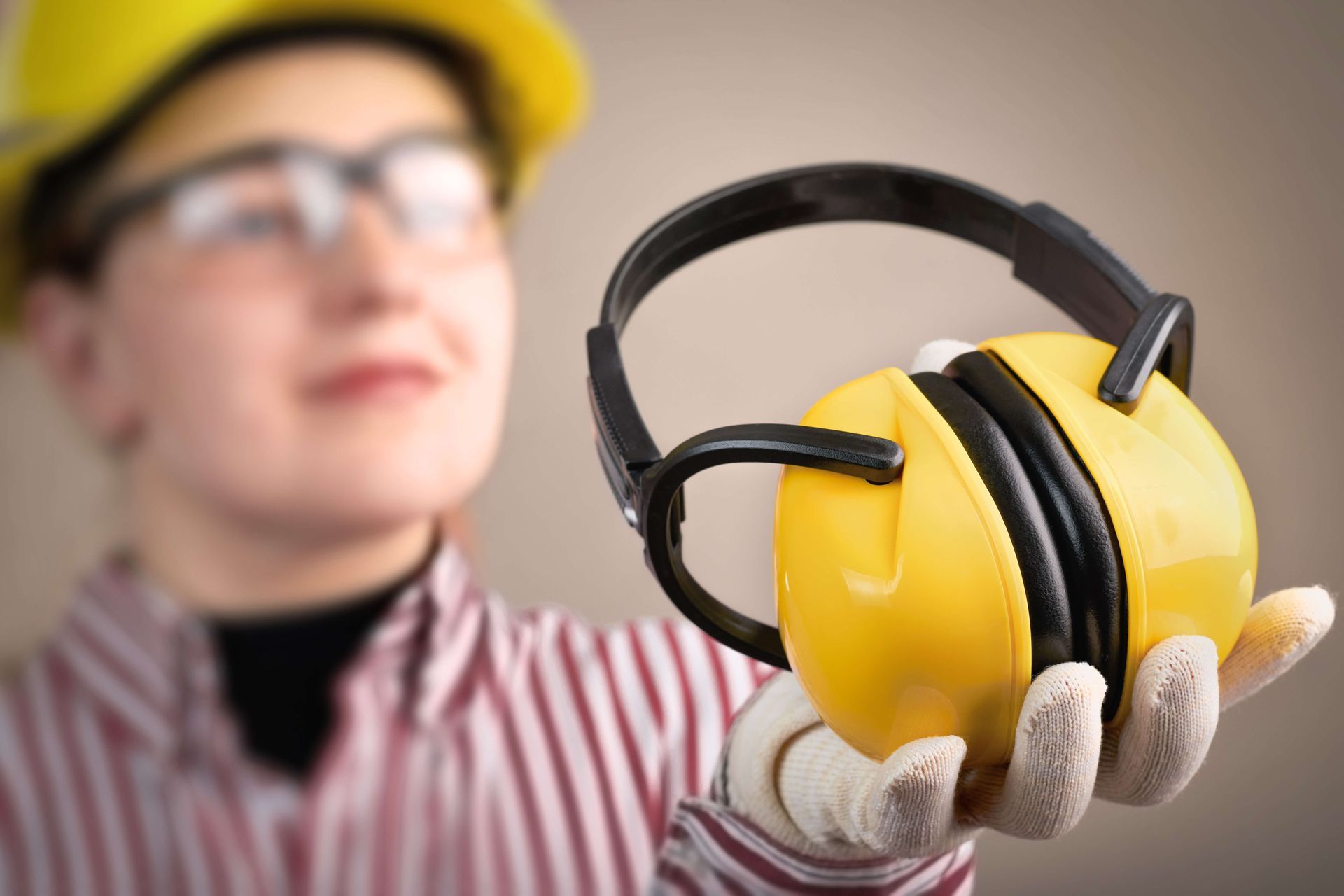worker holding ear muffs for hearing protection