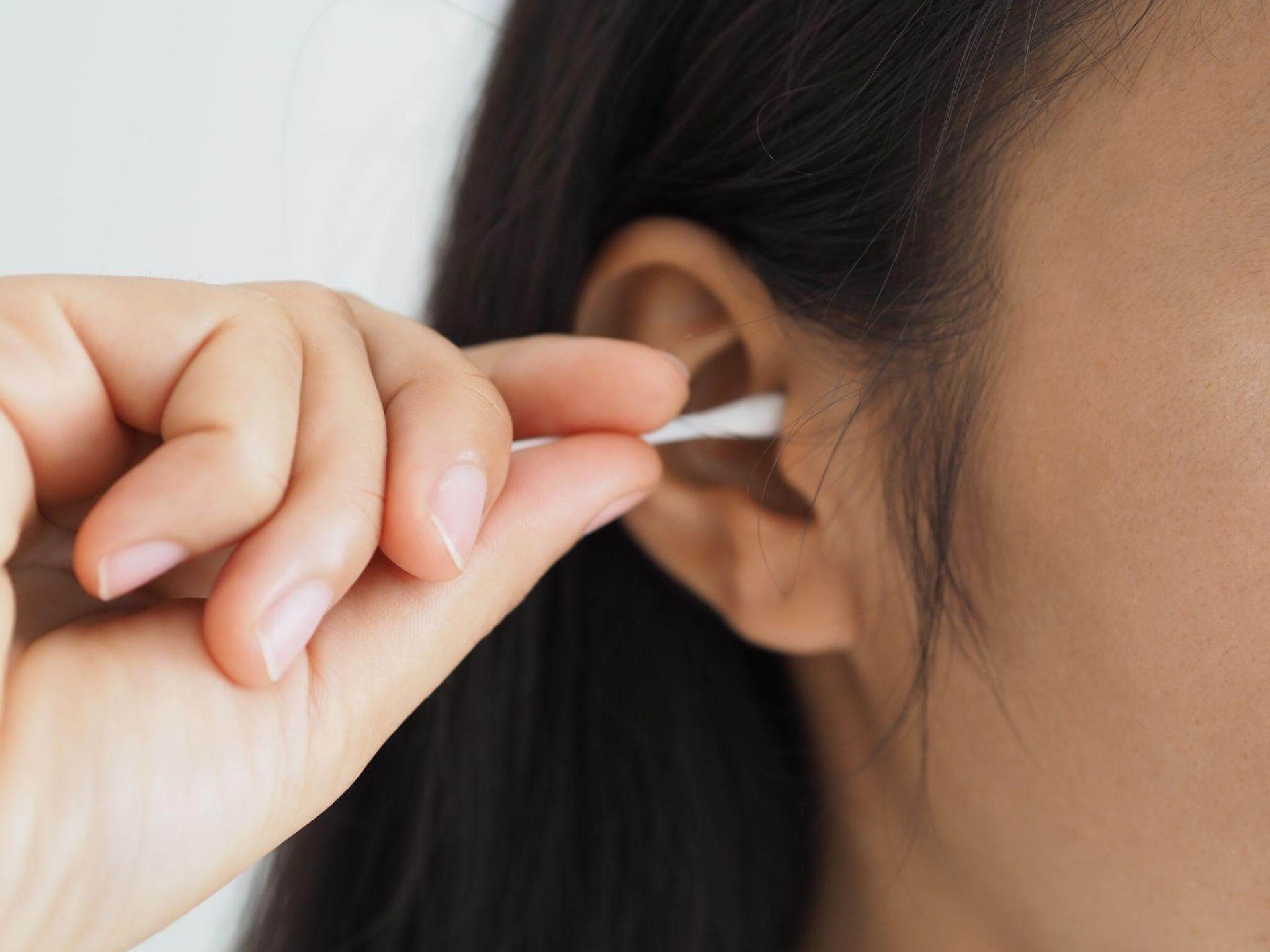woman using q-tip to clear ear wax