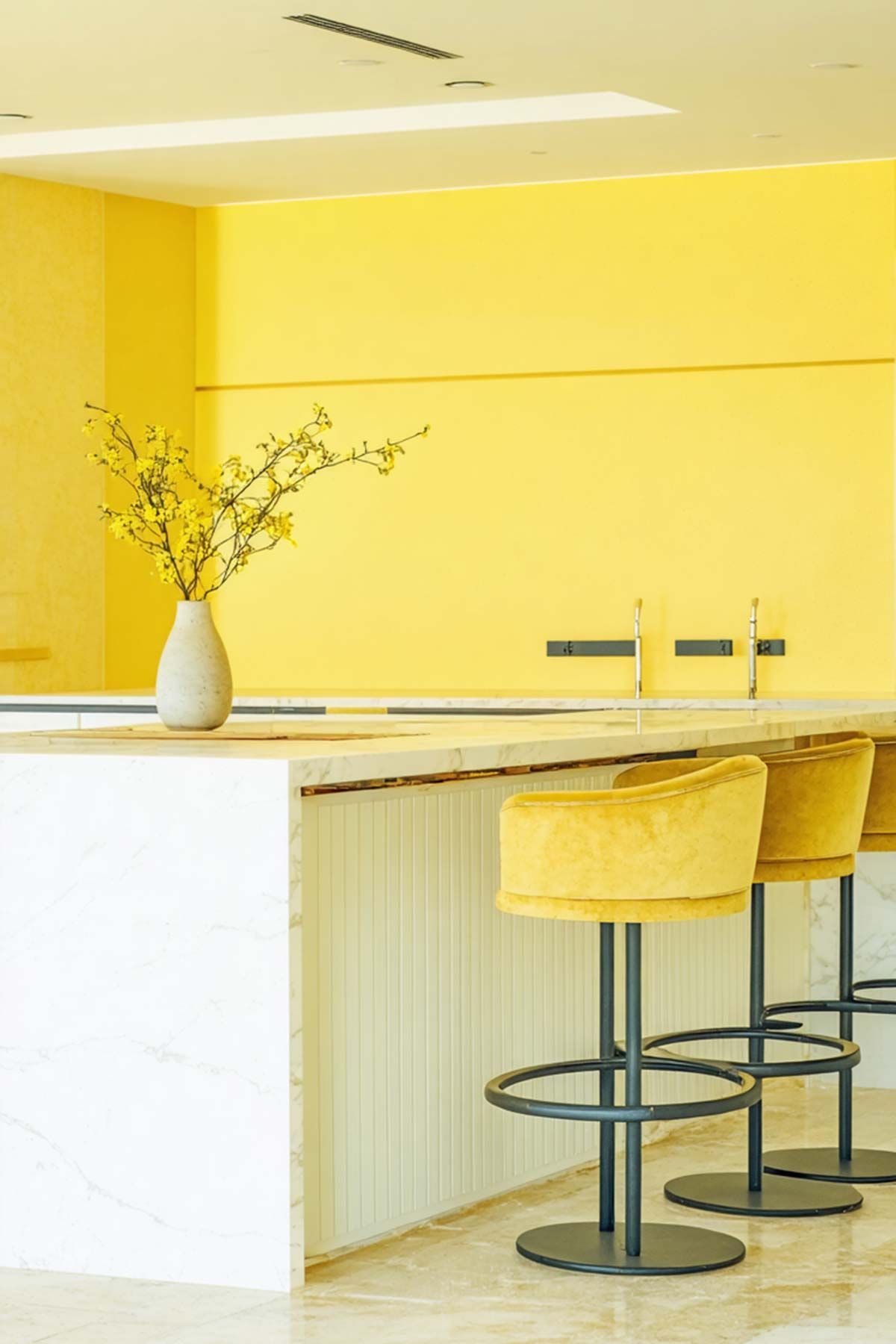 A kitchen with yellow walls and yellow bar stools.