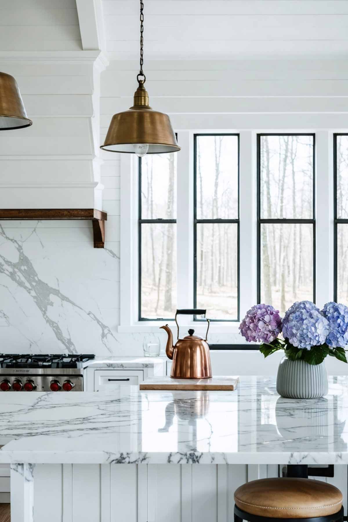 A kitchen with a marble counter top , a copper tea kettle , and a vase of flowers.