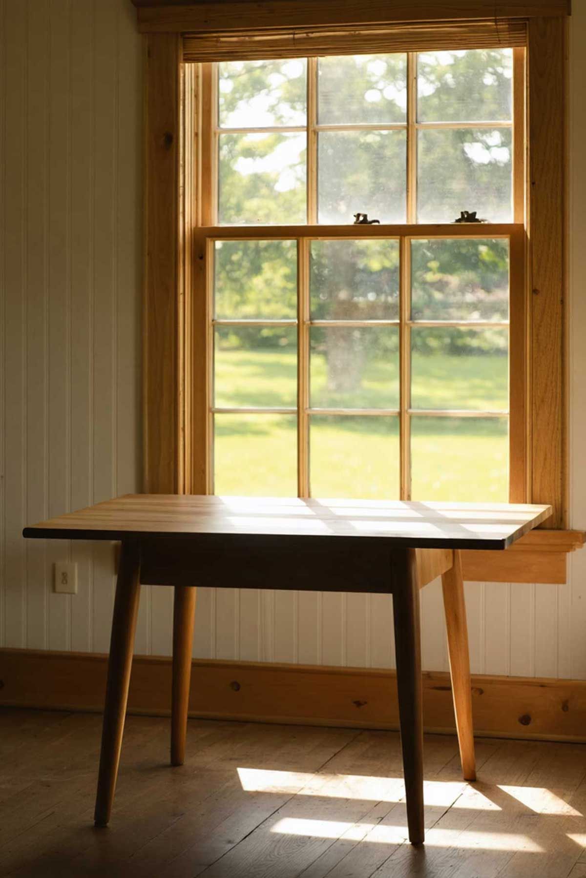 Shaker style kitchen table under an open window in a kitchen.