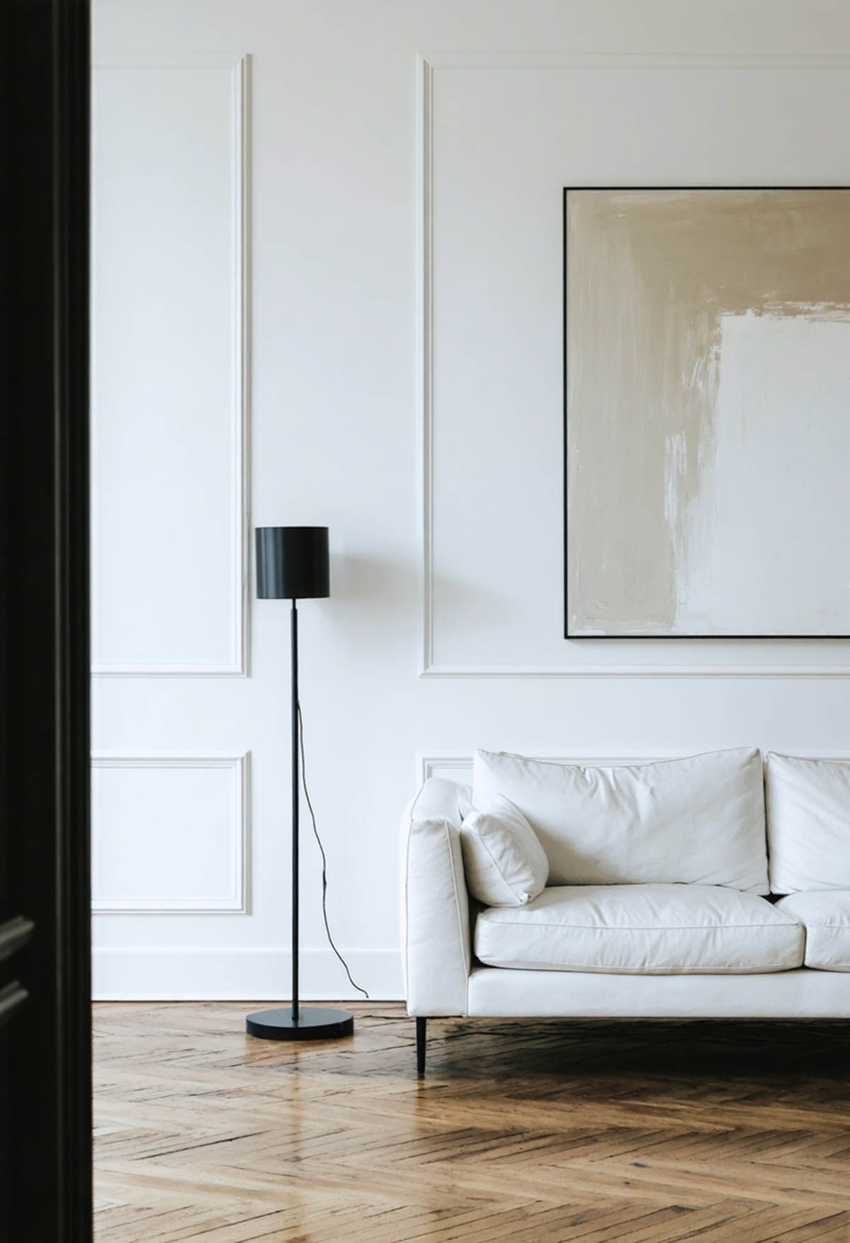 The_Role_of_Negative_Space_in_Modern_Interiors_0002 An all white living room with light timber floors, a white sofa and wall paneling.