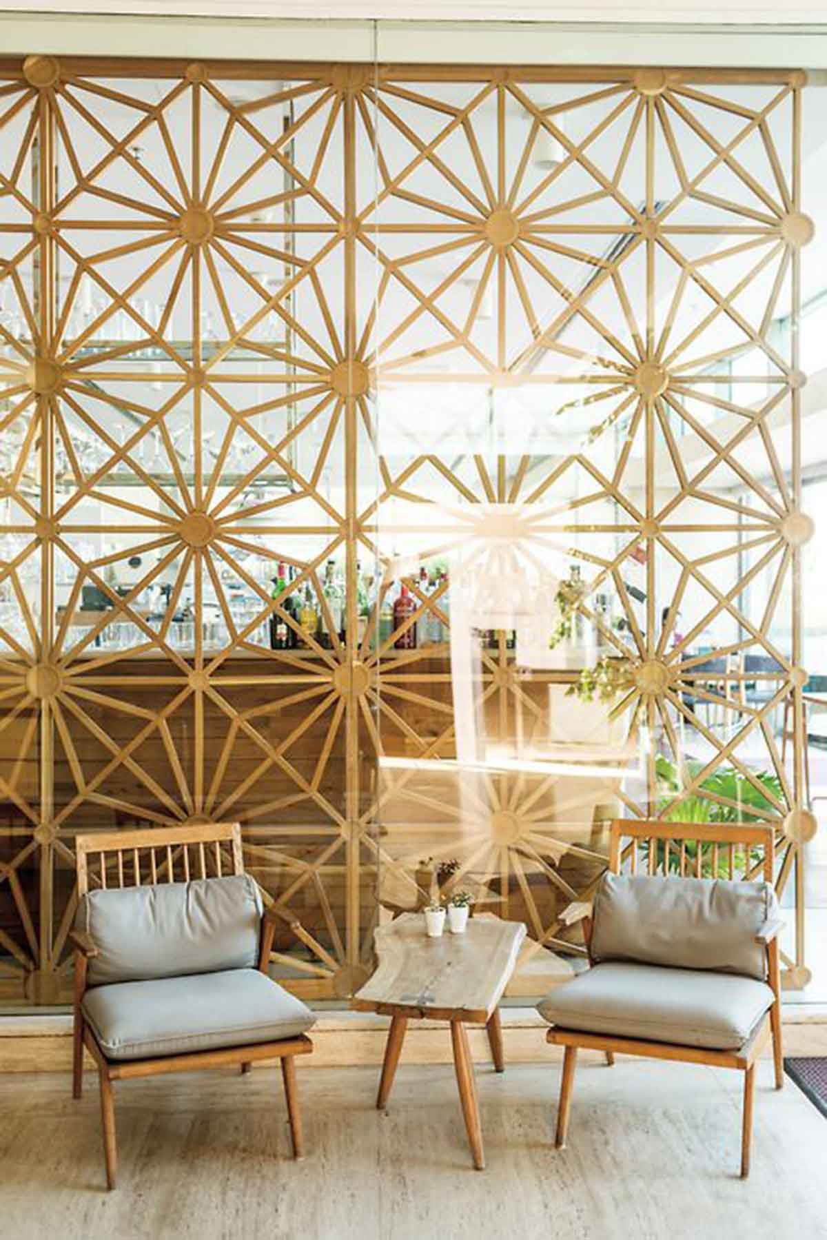 There are two chairs and a table in front of a wall with a pattern on it.