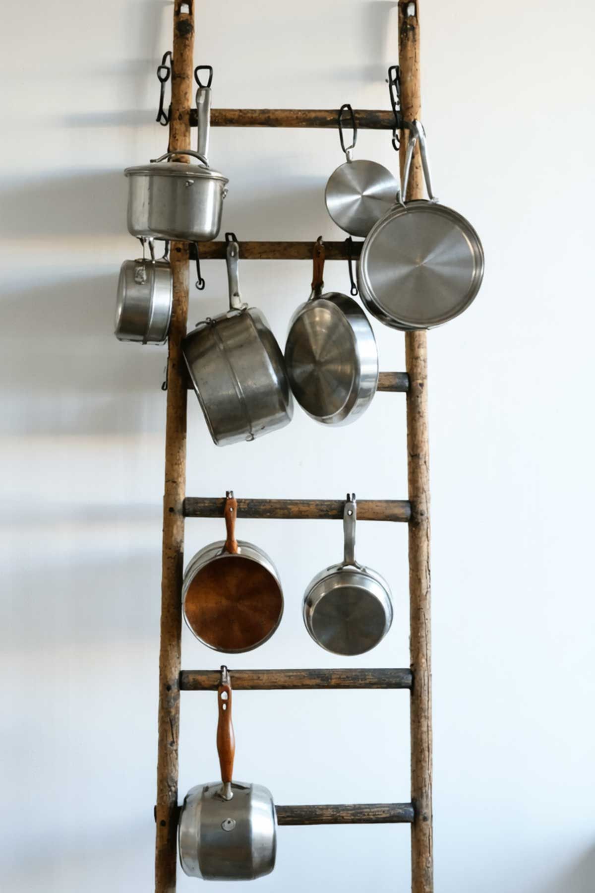 A wooden ladder with pots and pans hanging from it.