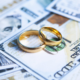 Two golden rings signifying marriage on top of money about to go through a divorce