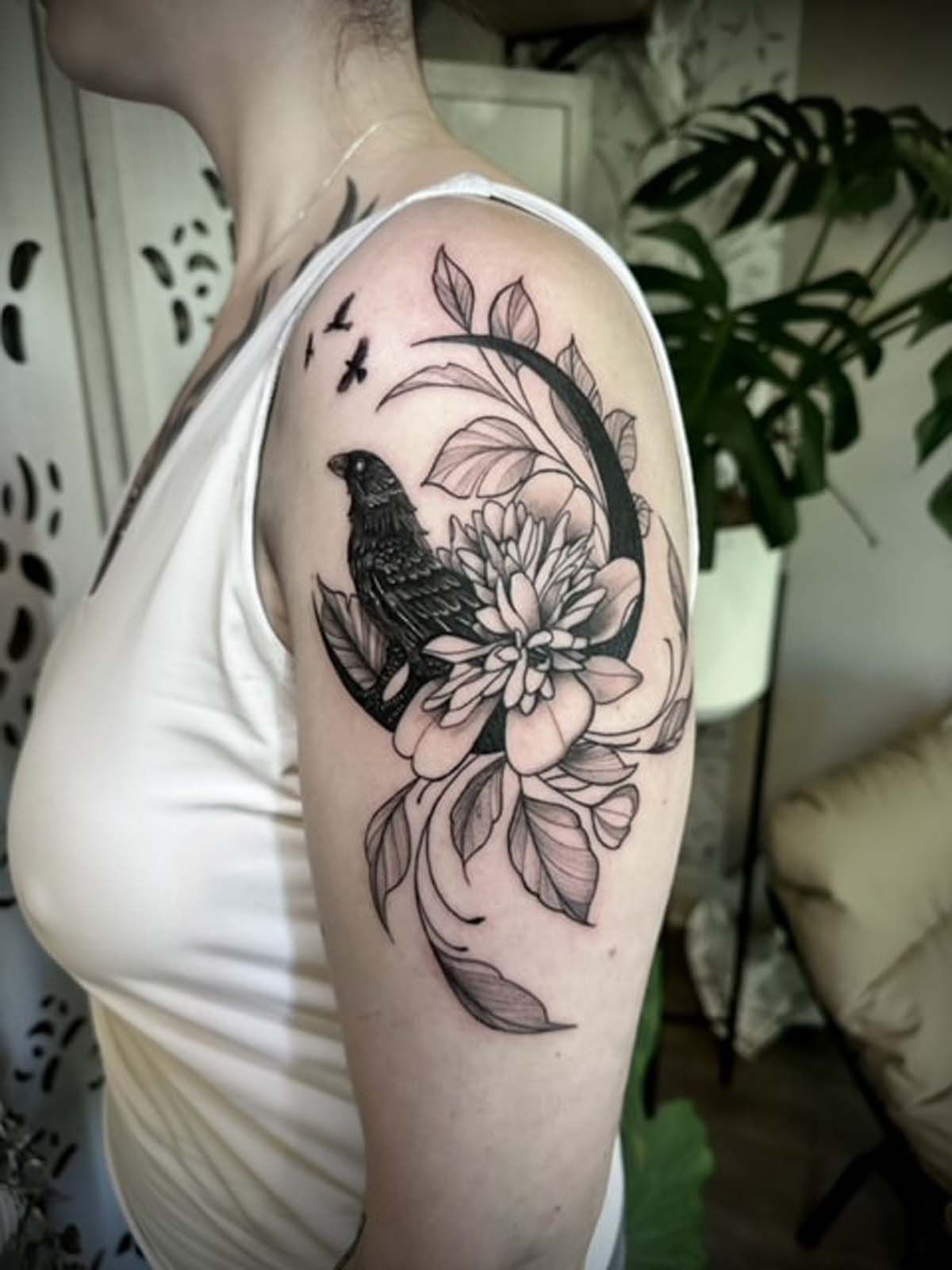 A woman has a tattoo of a bird and flowers on her arm.