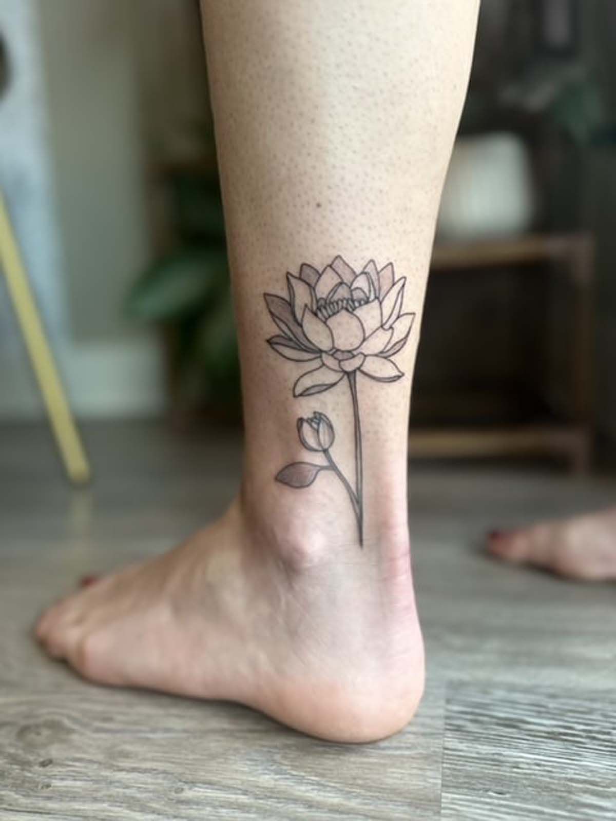 A woman has a tattoo of a lotus flower on her ankle.
