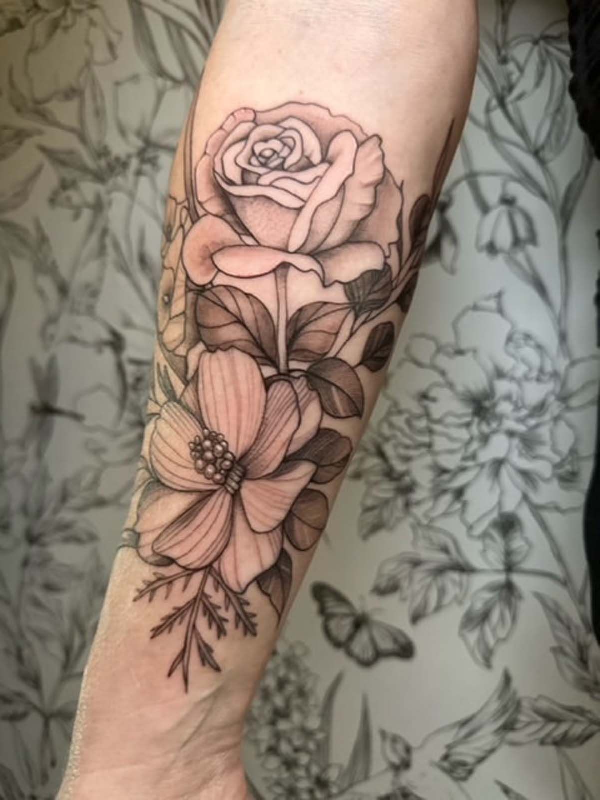 A woman has a tattoo of flowers on her forearm.