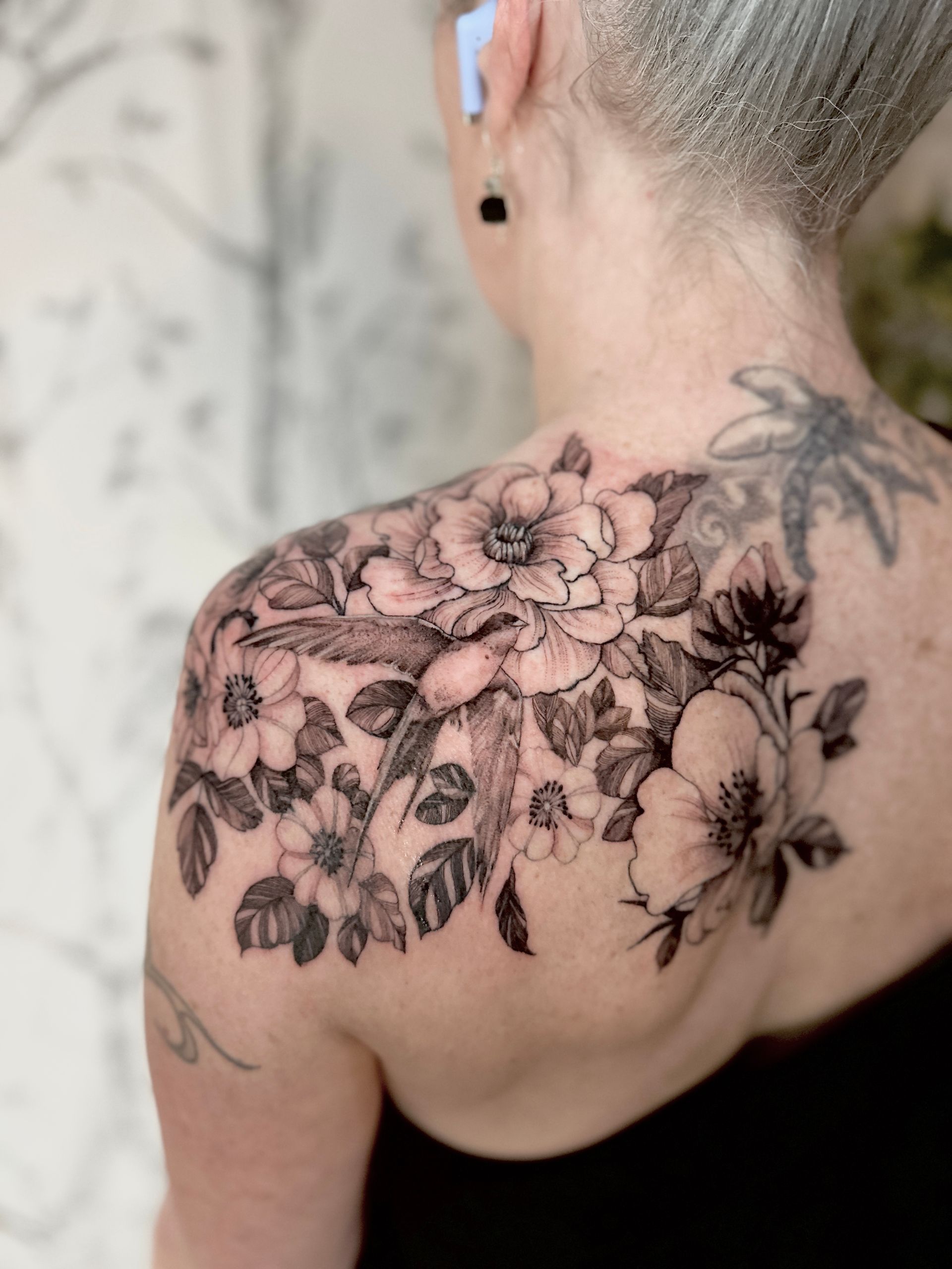 A woman has a tattoo of swallow with floral on her back