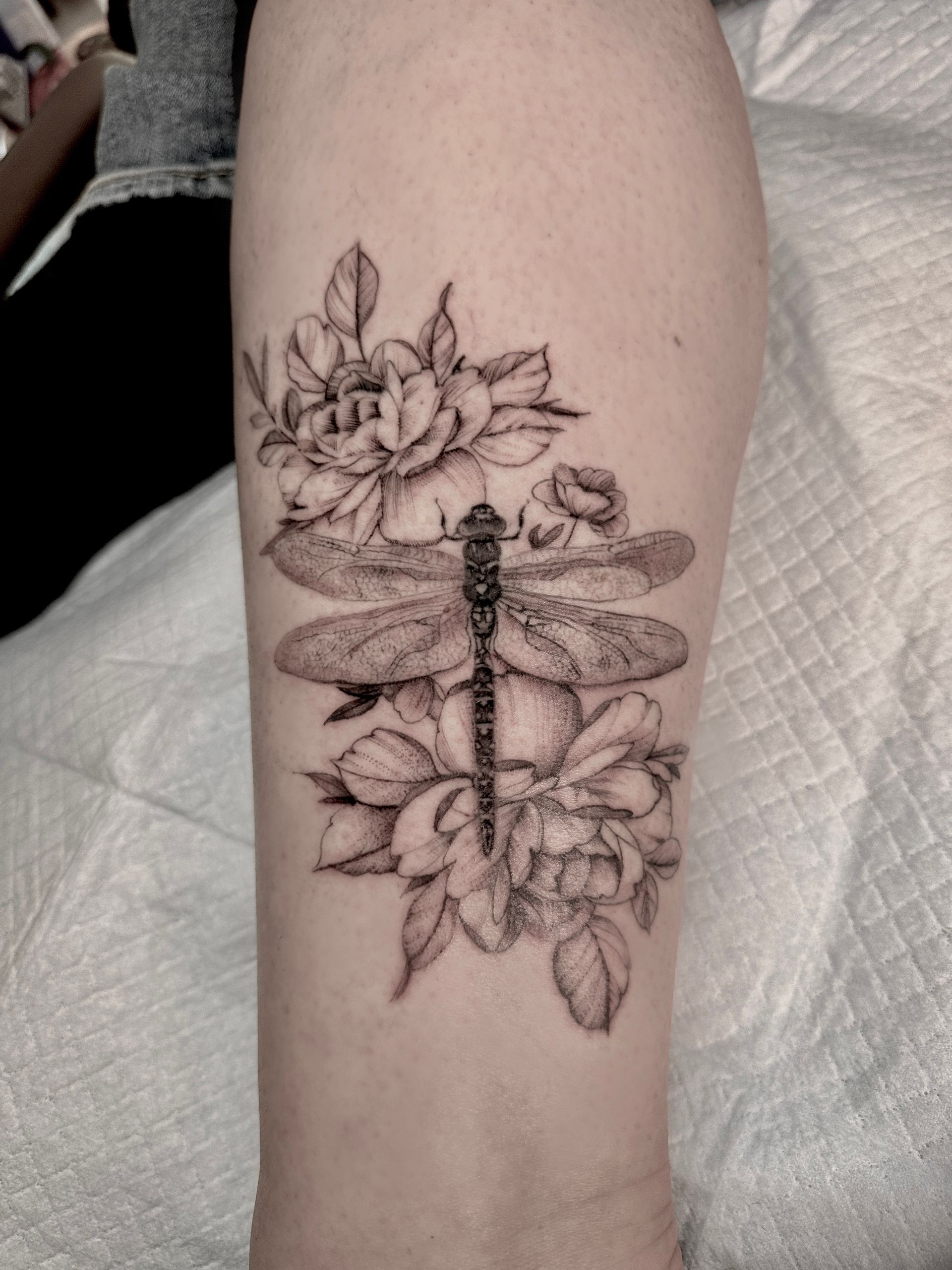 A woman has a tattoo of flowers and leaves on her forearm.