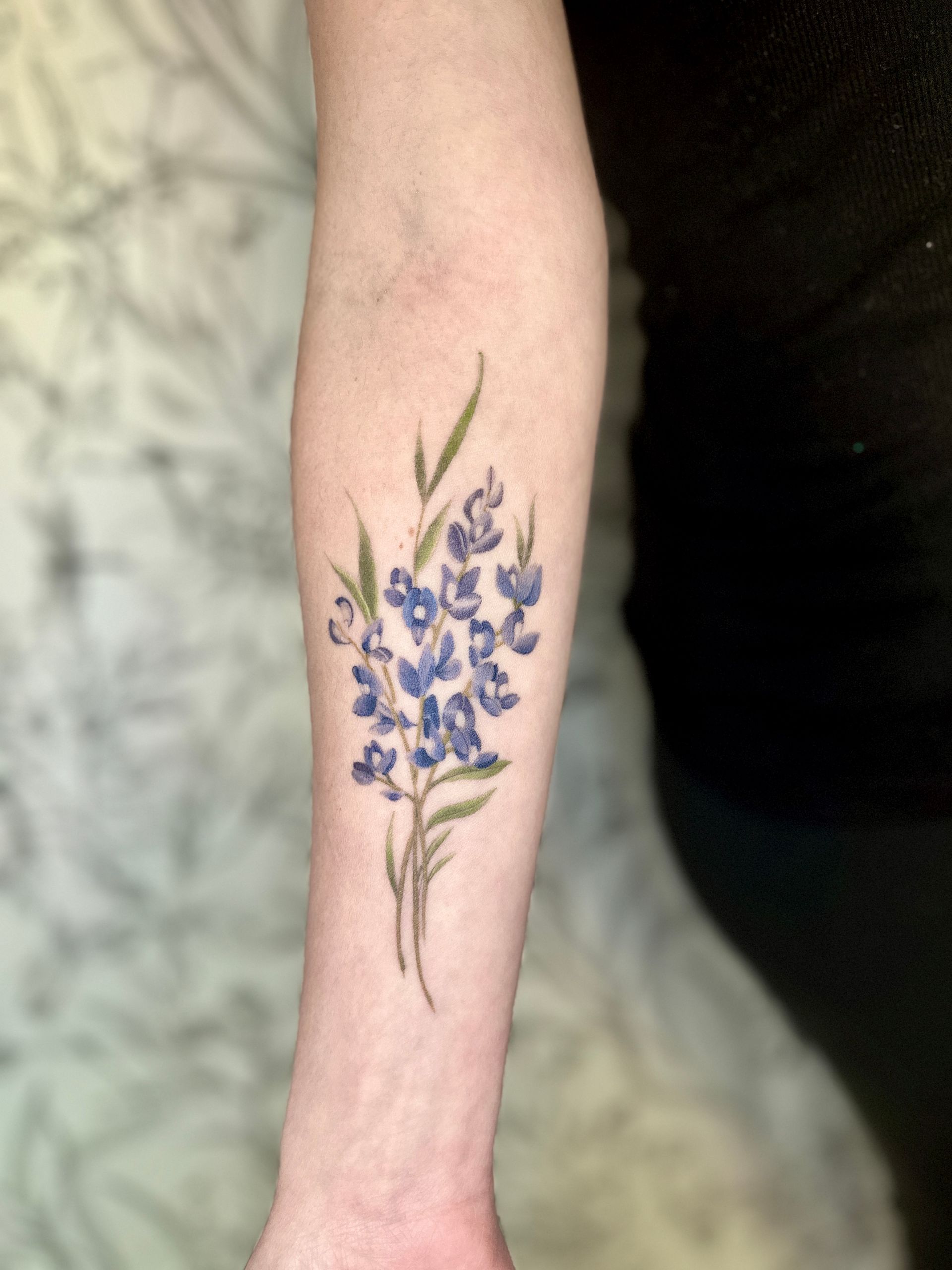 A woman has a tattoo of a hummingbird and flowers on her thigh