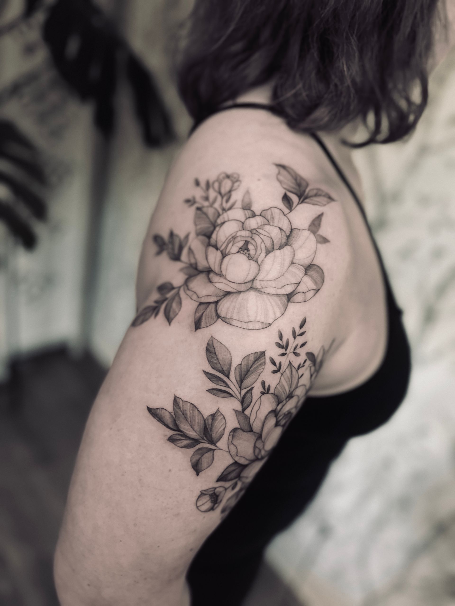 A woman has a tattoo of a hummingbird and flowers on her thigh