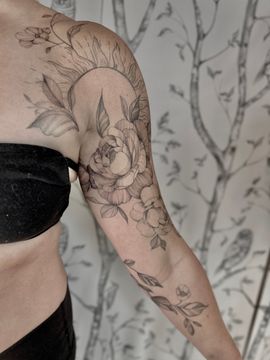 A woman has a tattoo of a hummingbird and flowers on her thigh